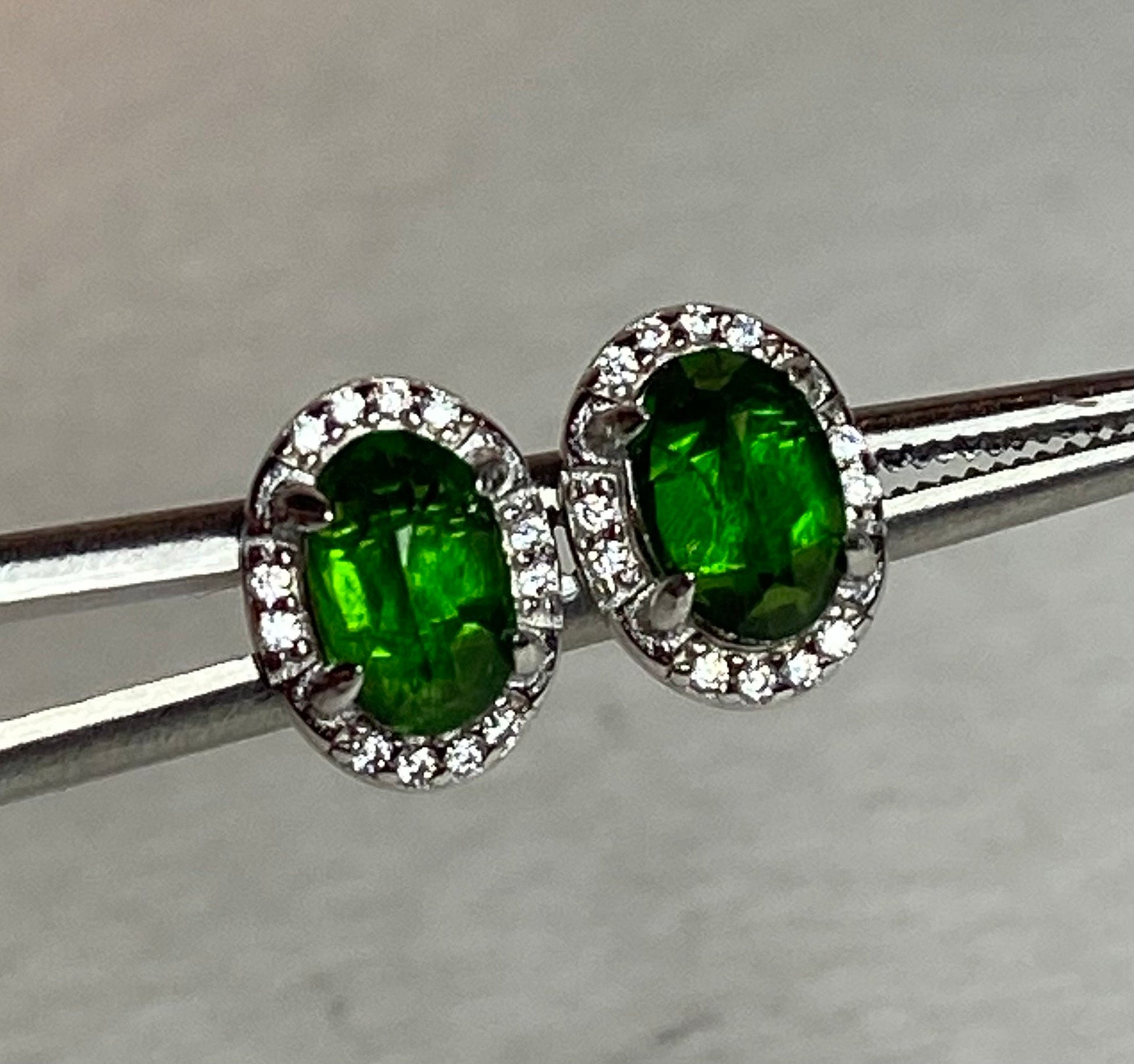 Sterling silver stud earrings with oval chrome diopside and diamond accents.