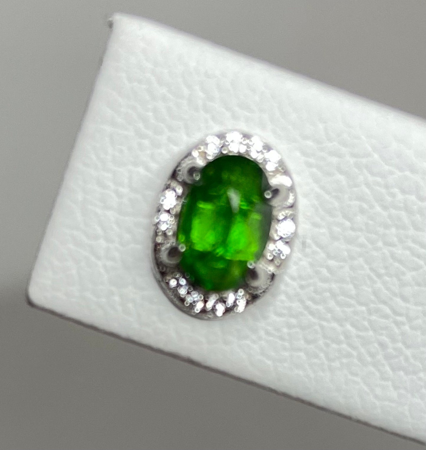 Sterling silver stud earrings with an oval chrome diopside center stone and a halo of small stones.