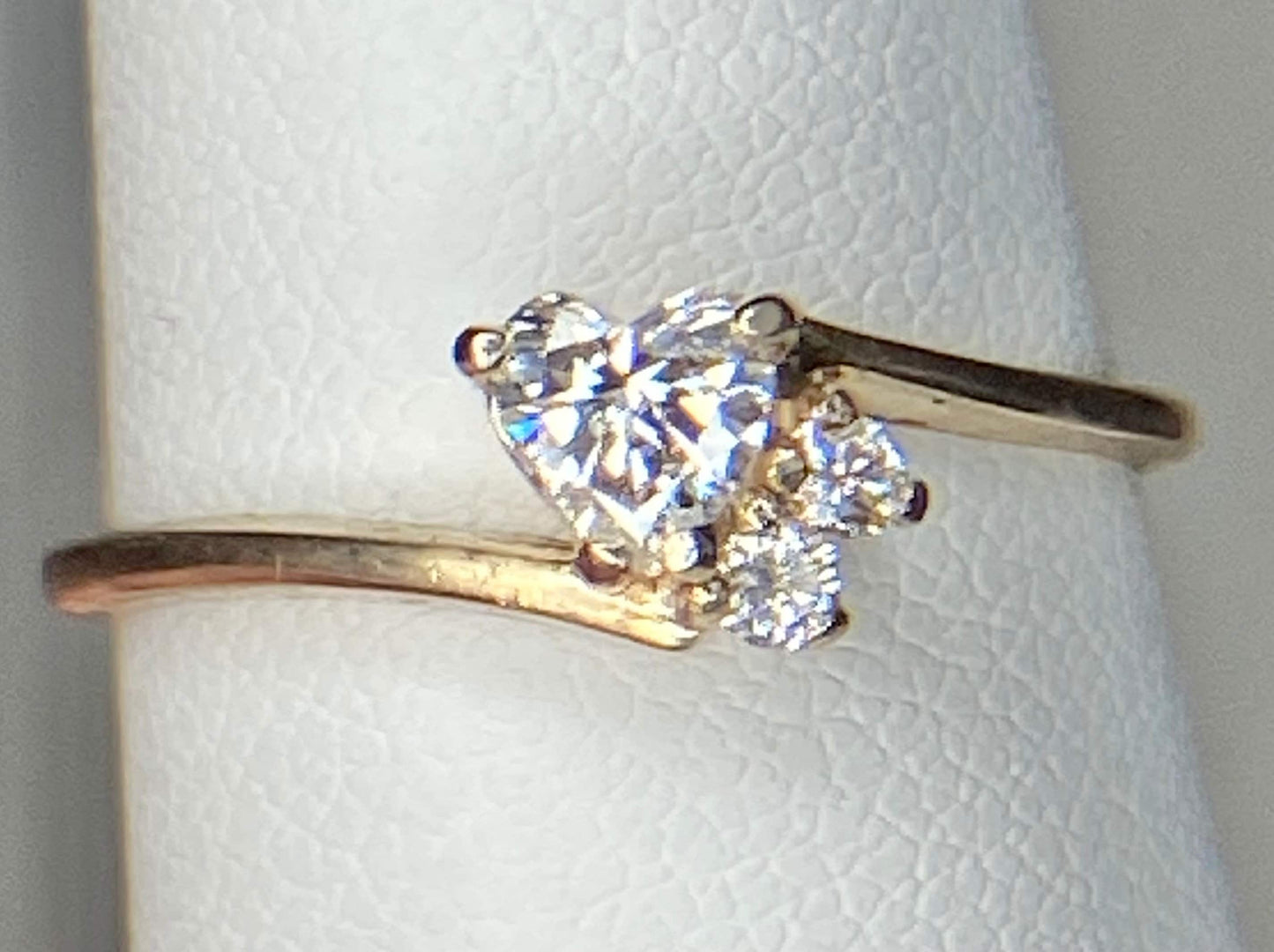 A 14k gold ring with a heart-shaped diamond and two accent diamonds.
