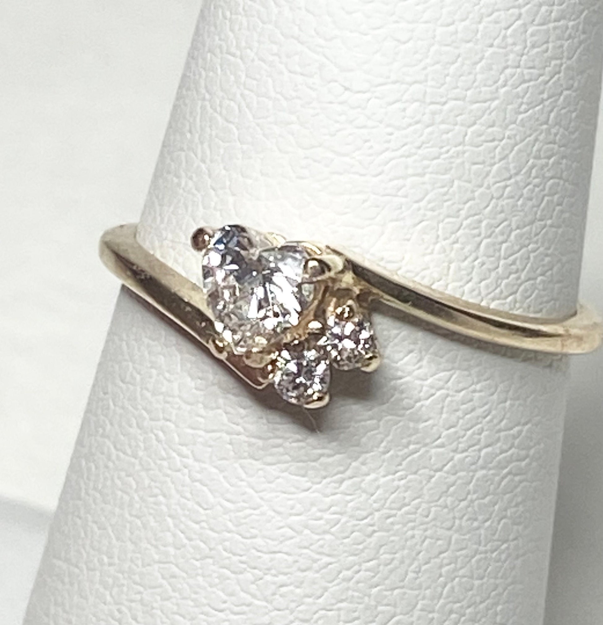 A 14k gold ring with a heart-shaped diamond and two accent diamonds.