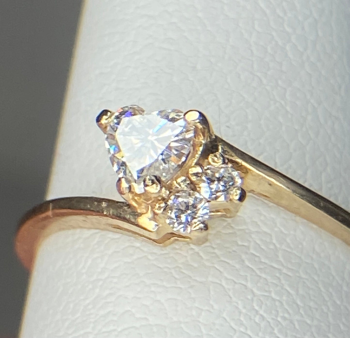 A 14k gold ring with a heart-shaped diamond and two accent diamonds.
