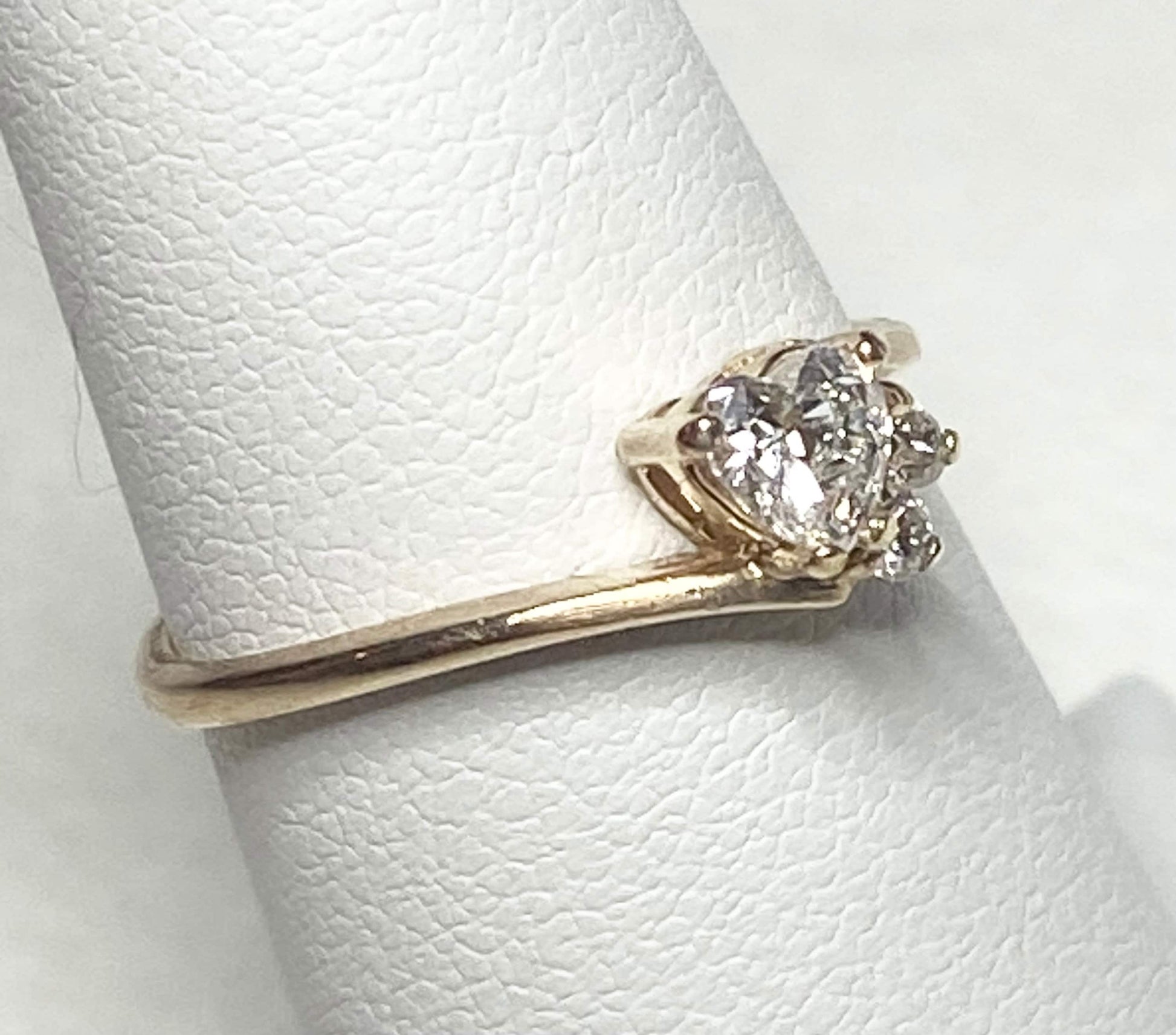 A 14k gold ring with a heart-shaped diamond and two accent diamonds.