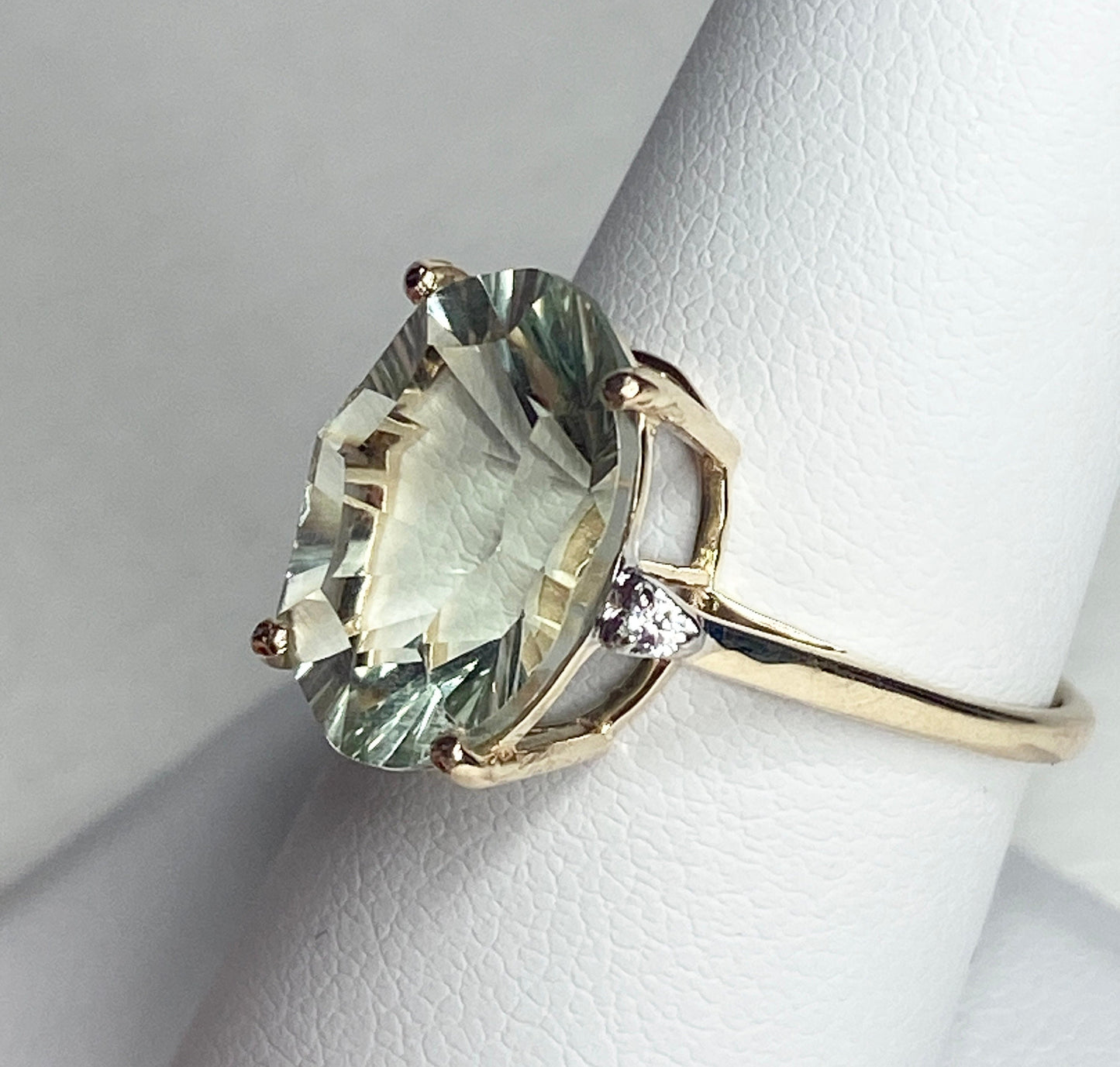 A 9k yellow gold ring with a large oval prasiolite quartz and two zircons.