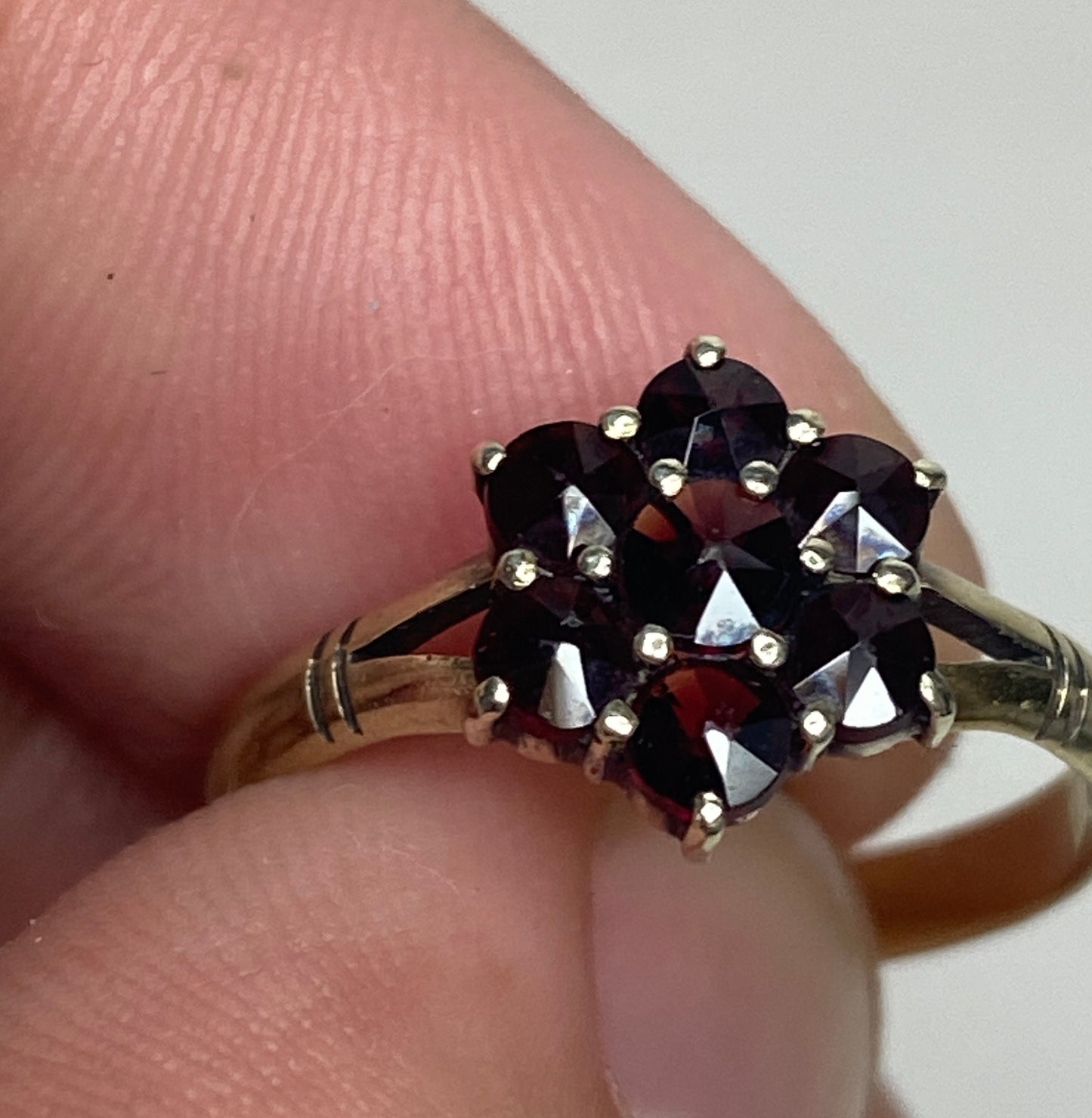 A 14k gold ring with a cluster of seven rose-cut garnets in a daisy design.
