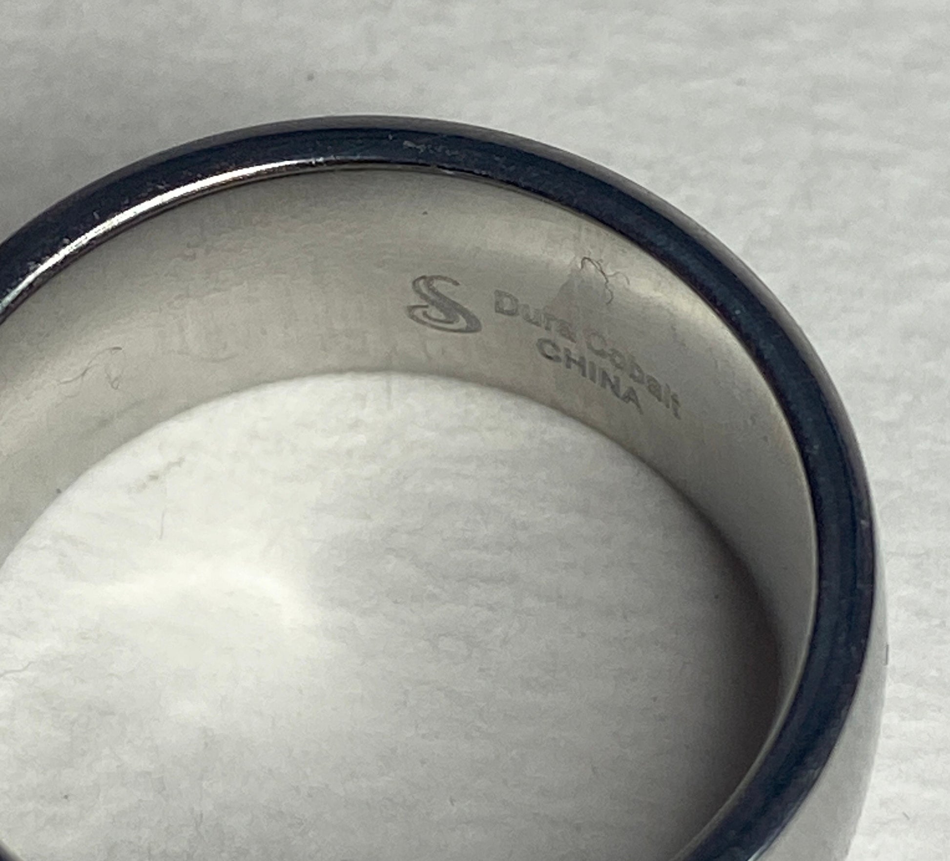 A wide, silver-toned ring with "Dura Cobalt CHINA" inscribed inside.