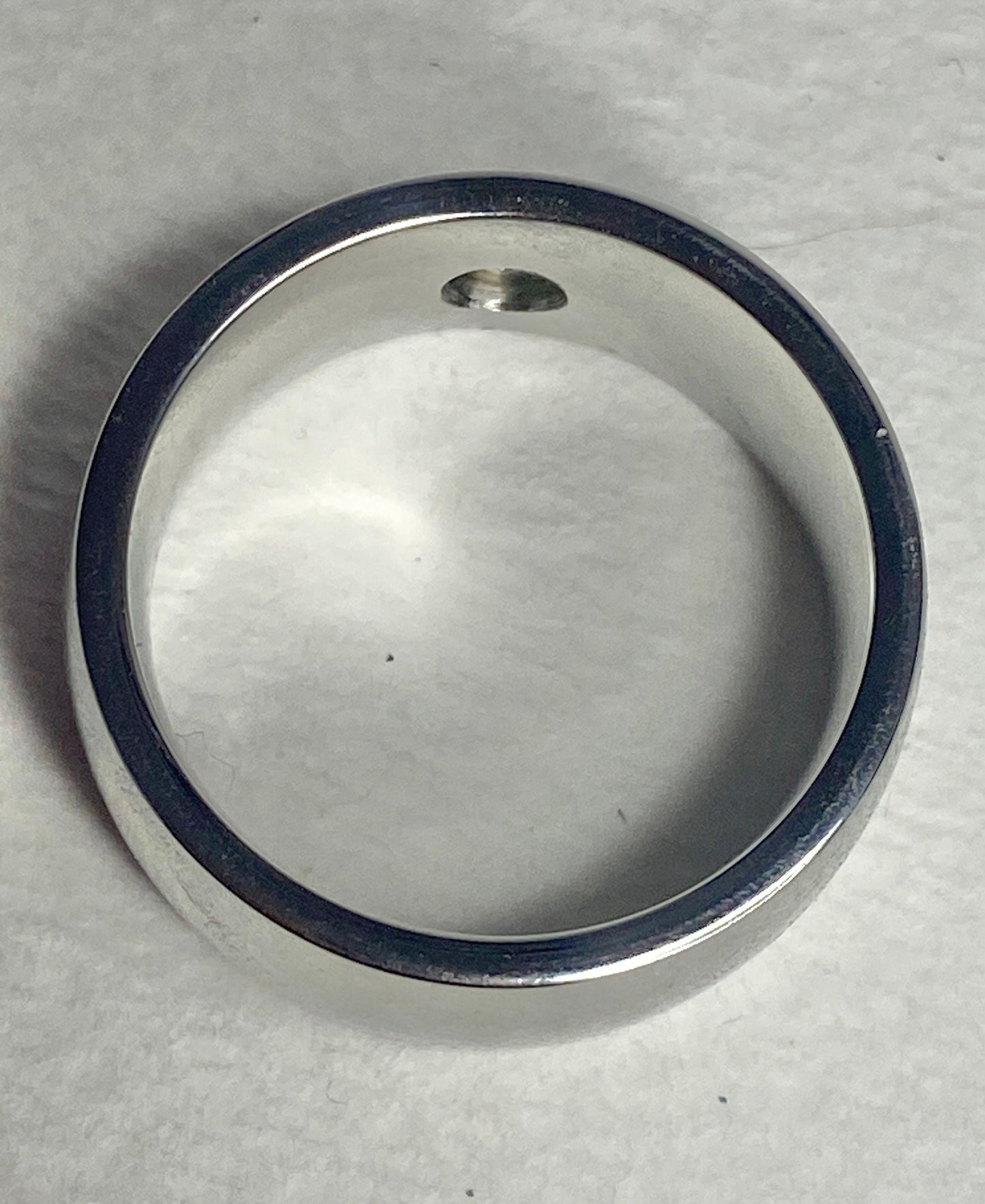 A wide, silver-toned band ring with a small diamond.