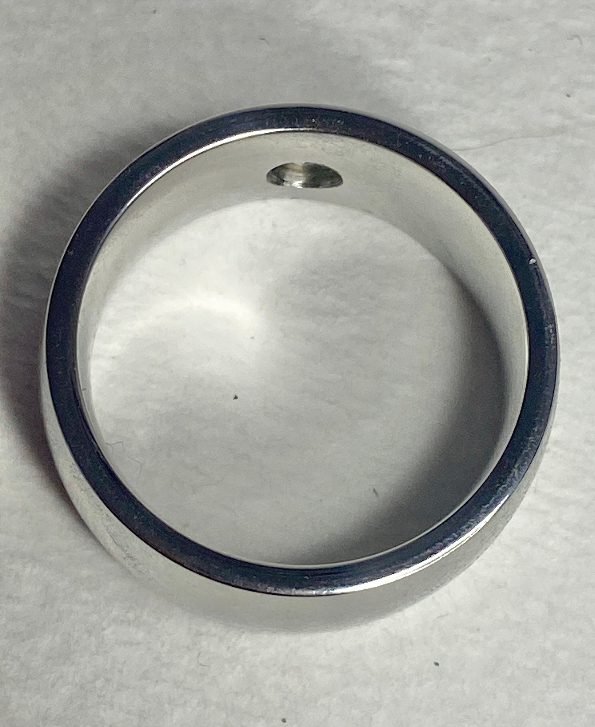 A wide, silver-toned band ring with a small diamond.