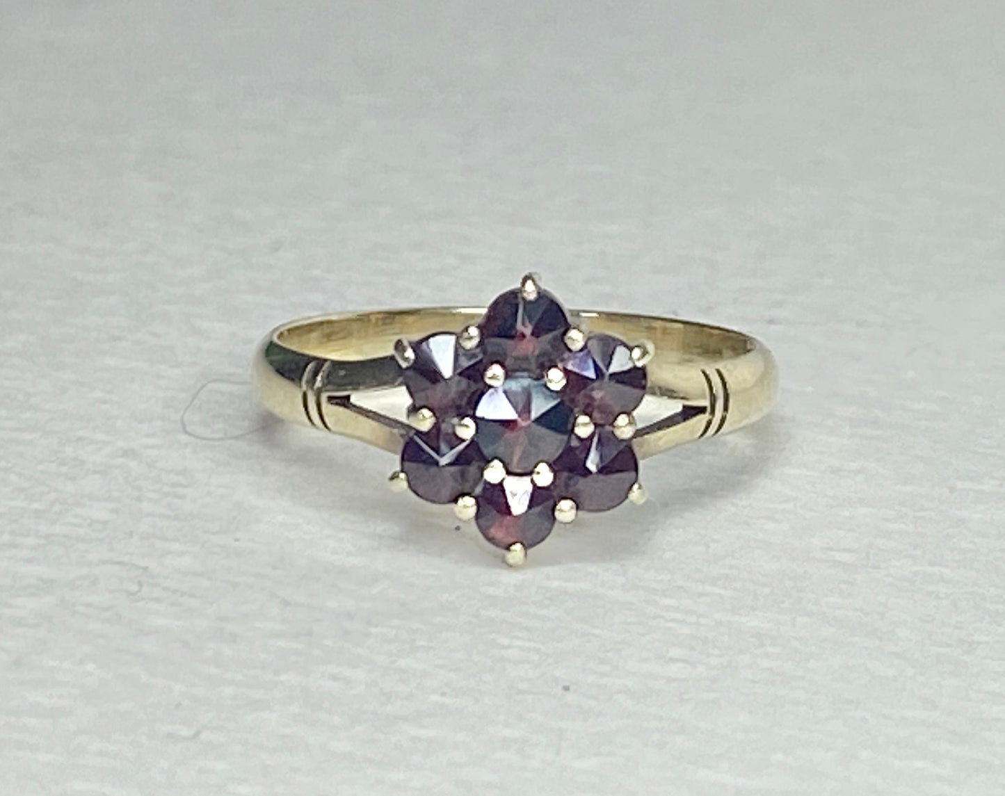 A 14k yellow gold ring with a cluster of seven rose-cut garnets in a daisy design.