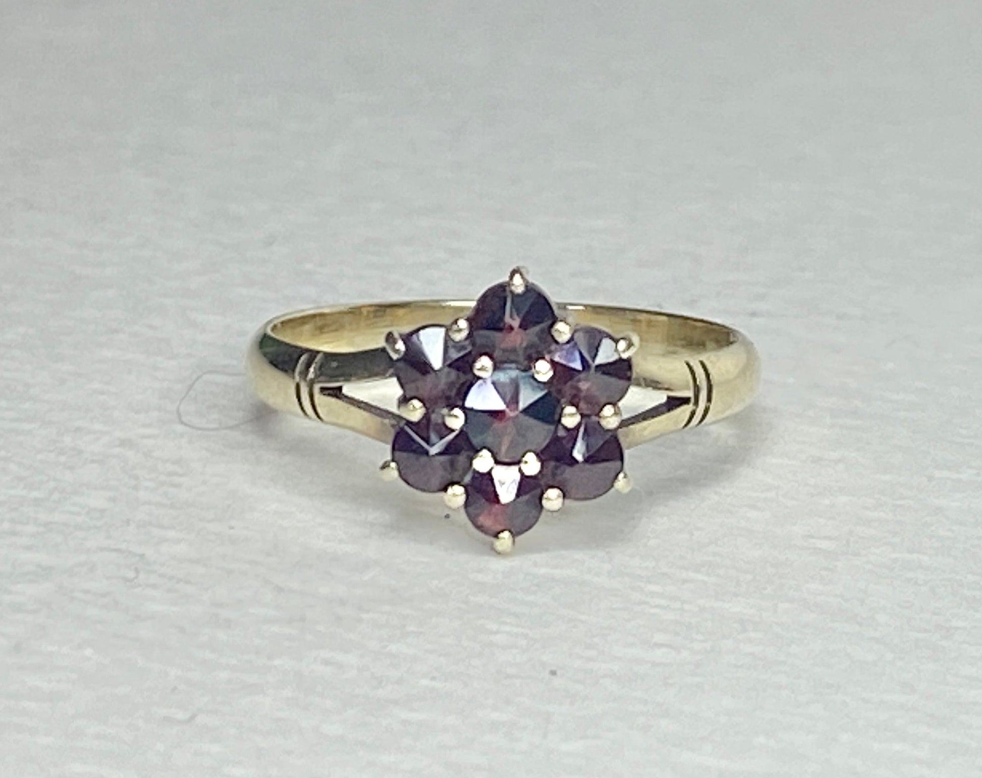 A 14k yellow gold ring with a cluster of seven rose-cut garnets in a daisy design.