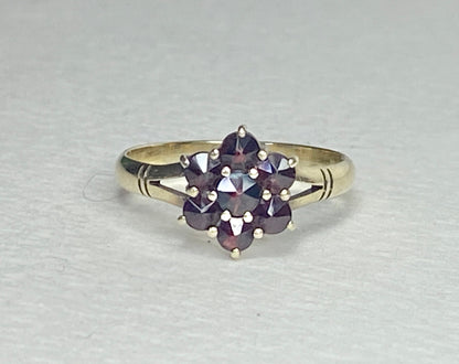 A 14k yellow gold ring with a cluster of seven rose-cut garnets in a daisy design.