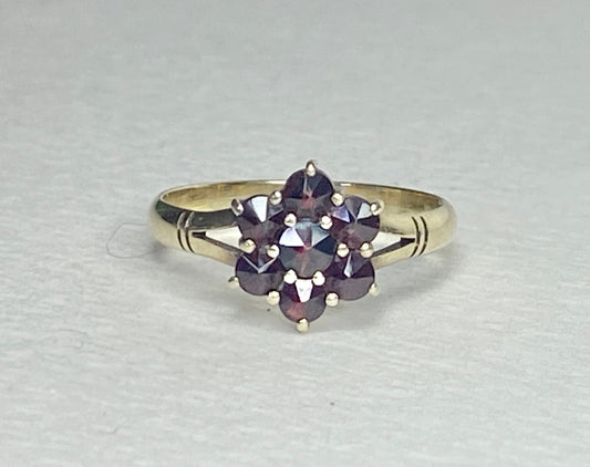 A 14k yellow gold ring with a cluster of seven rose-cut garnets in a daisy design.