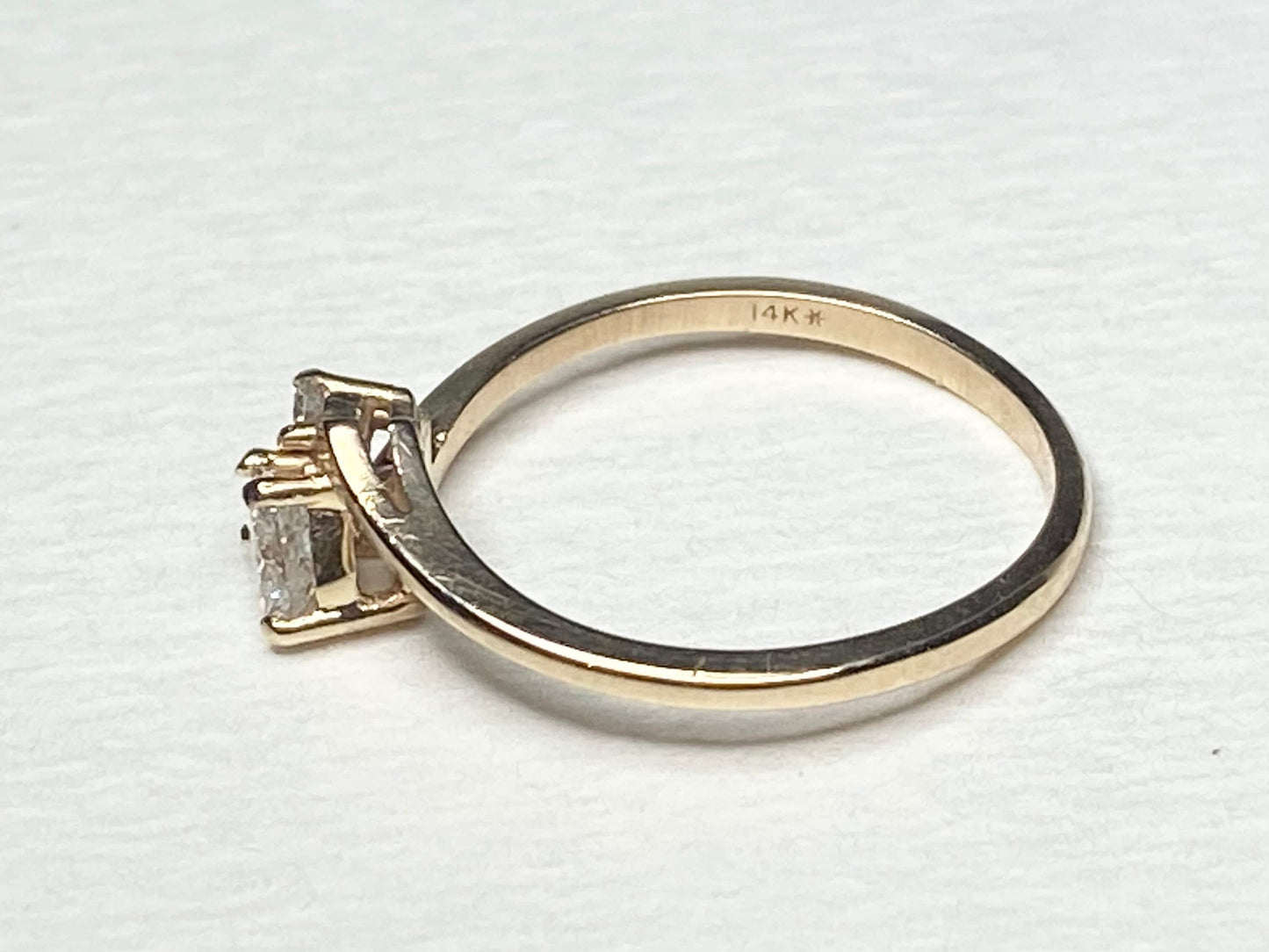 A 14k gold ring with a heart-shaped diamond and two accent diamonds.