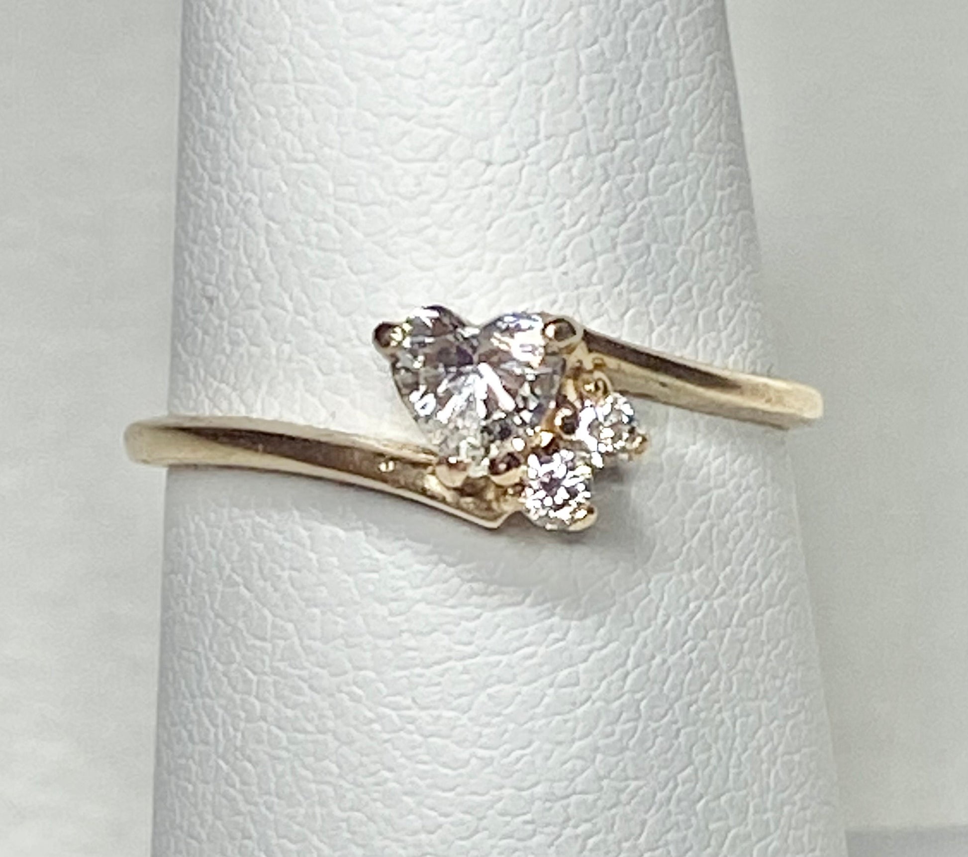 A 14k gold ring with a heart-shaped diamond and two smaller diamonds.