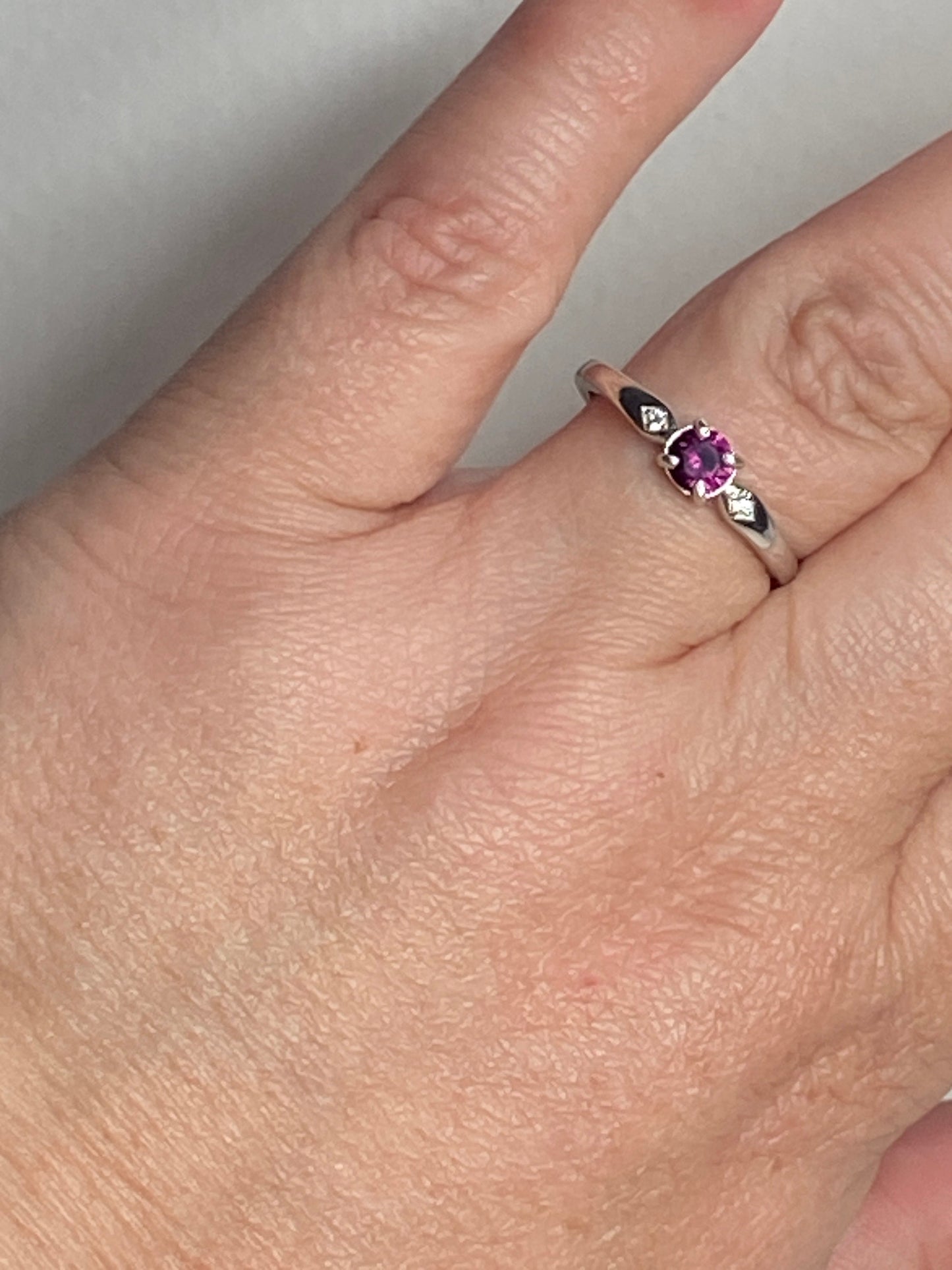 A sterling silver band ring with a purple rhodolite garnet and two small crystals.