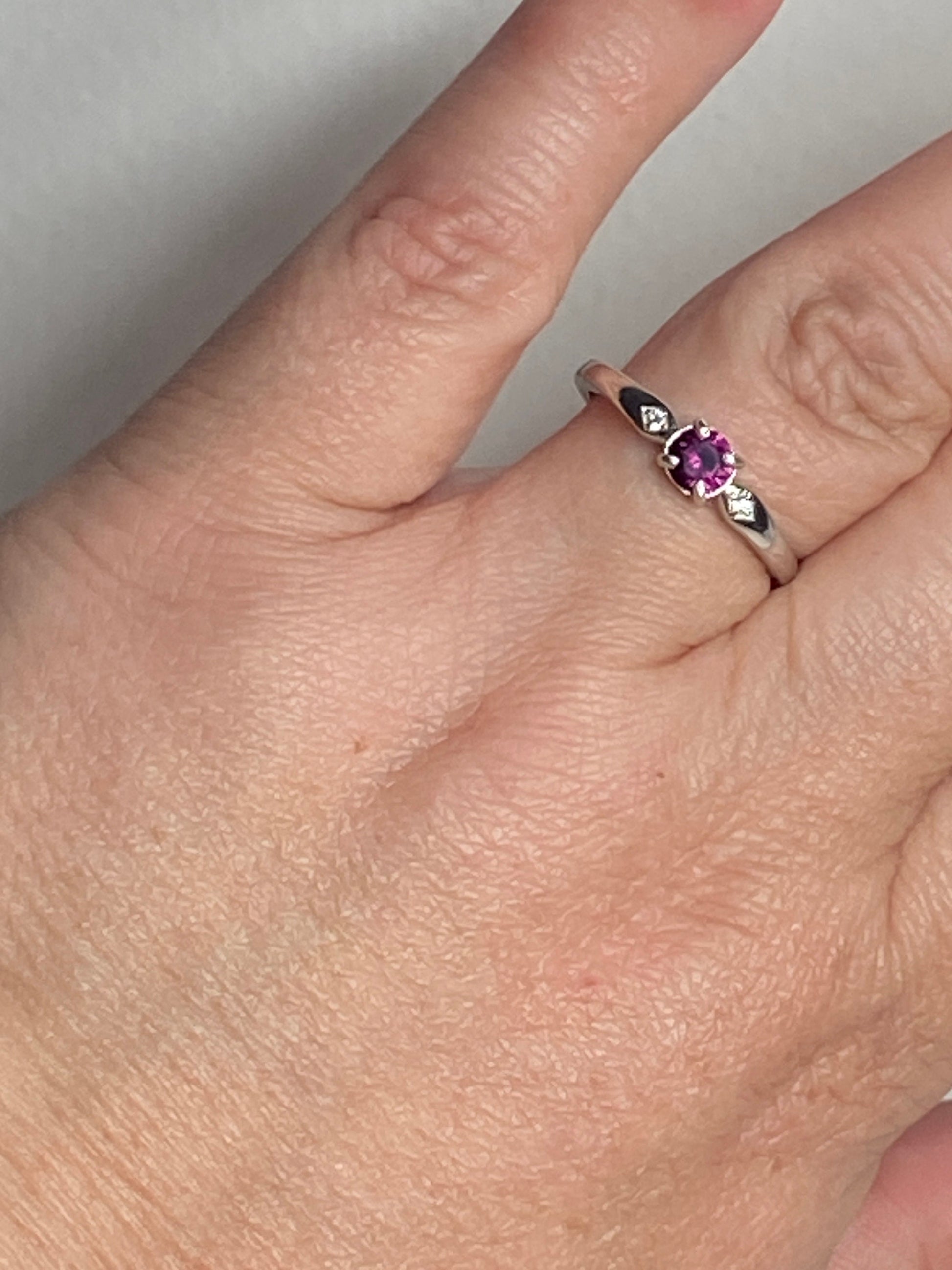 A sterling silver band ring with a purple rhodolite garnet and two small crystals.