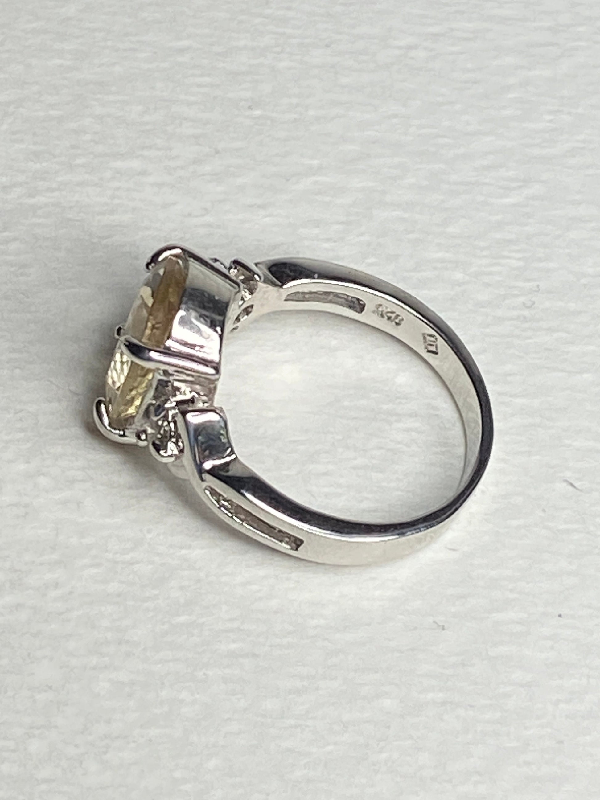 Sterling silver ring with a yellow oval sunstone and two small diamonds.
