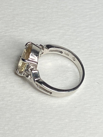 Sterling silver ring with a yellow oval sunstone and two small diamonds.