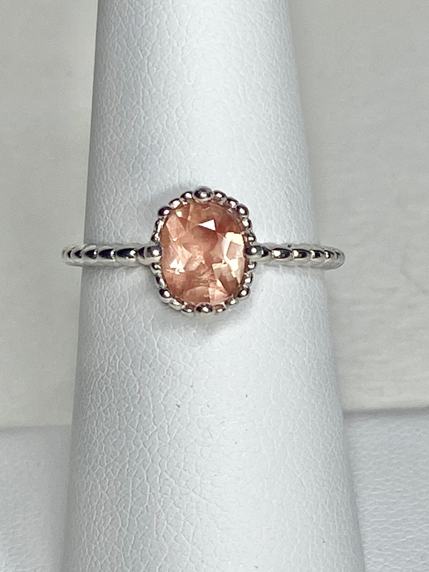 Sterling silver ring with a peach oval Oregon Sunstone in a beaded setting.