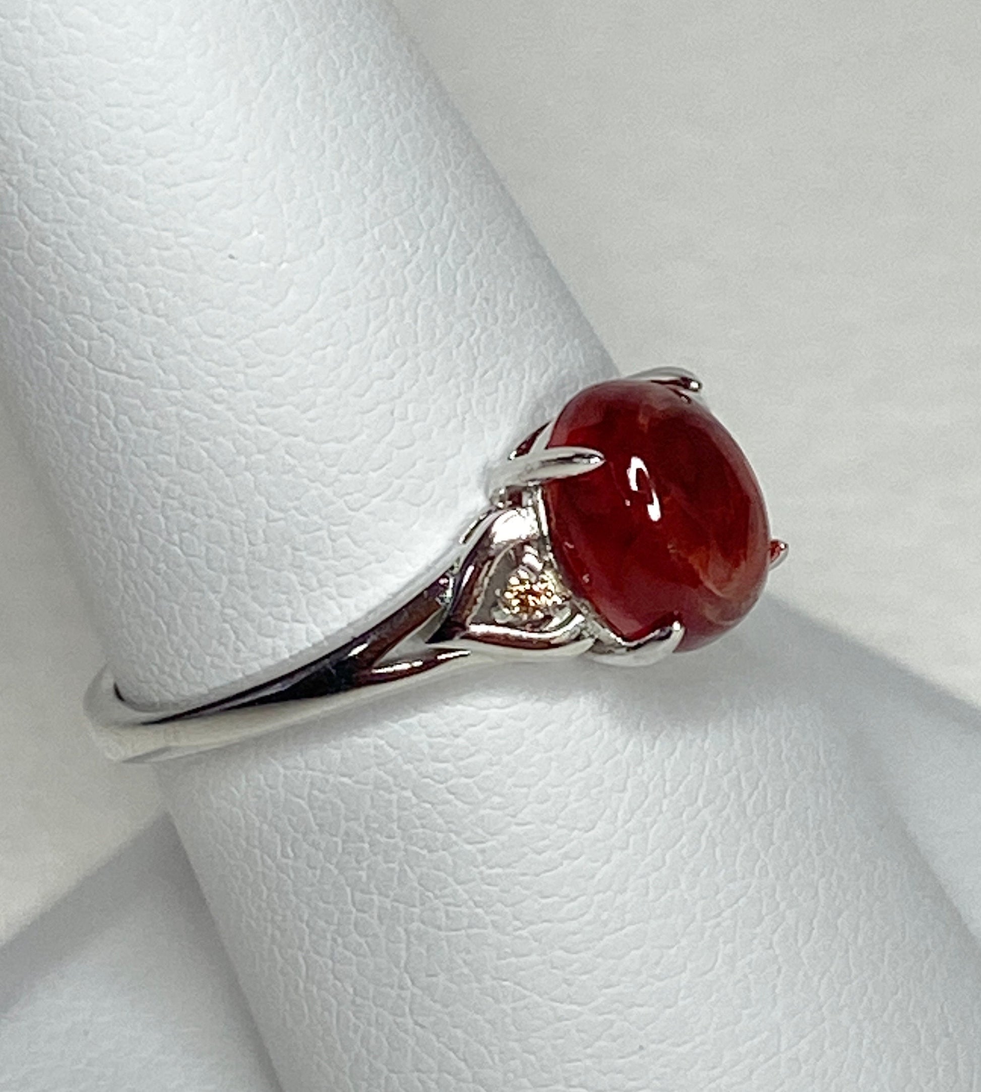 Sterling silver ring with a red oval Oregon sunstone and small brown diamonds.