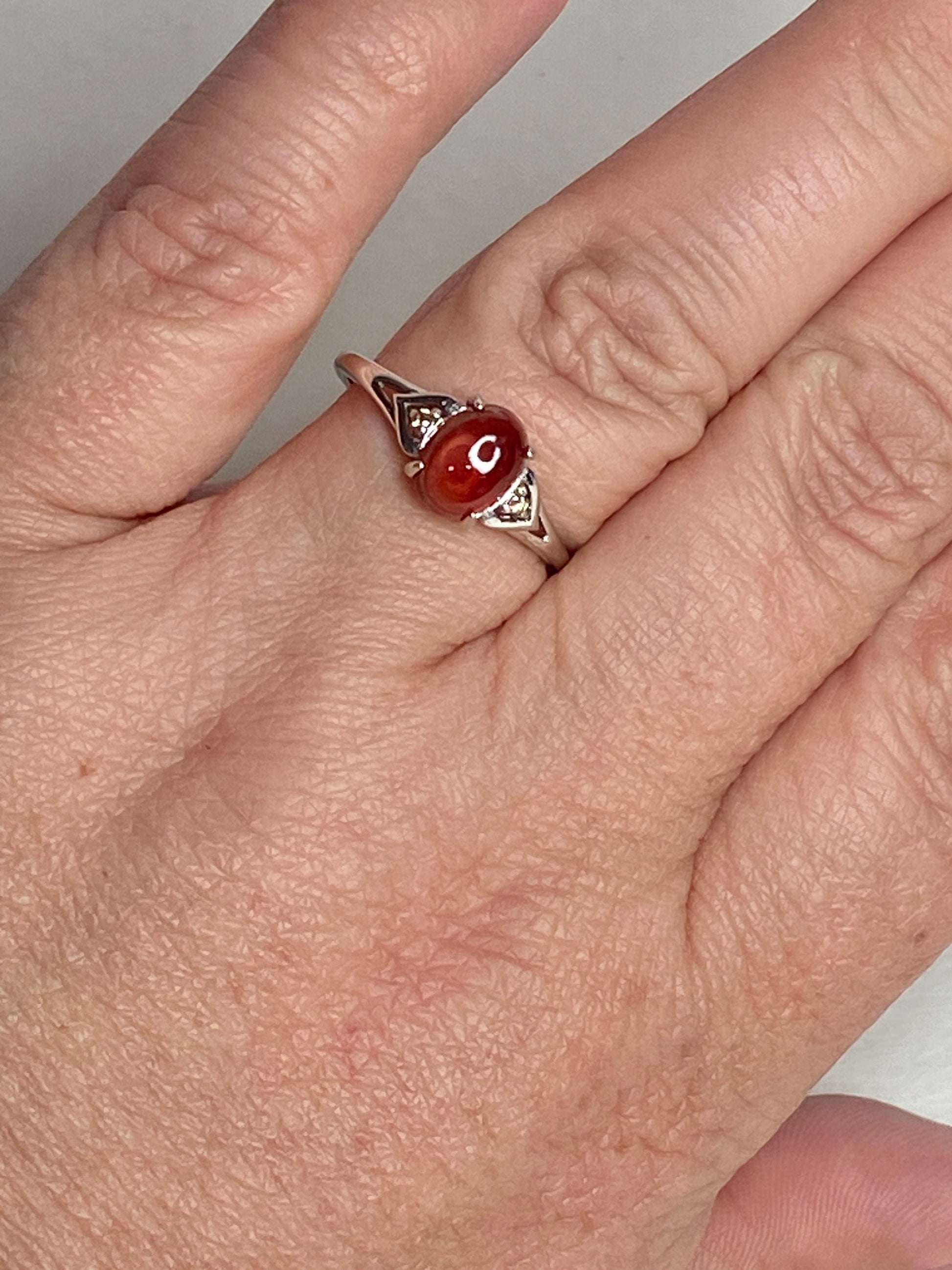 Sterling silver ring with oval red Oregon sunstone and small brown diamonds.
