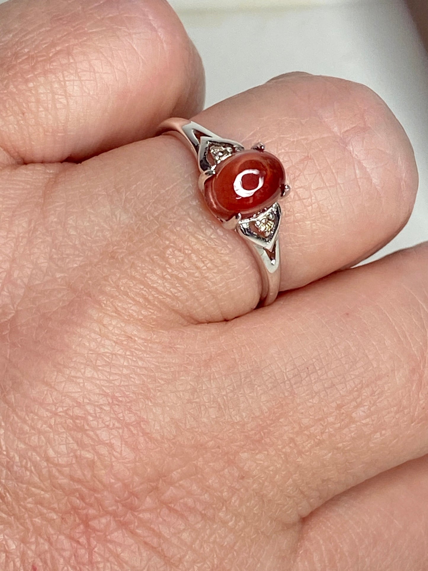 Sterling silver ring with oval red Oregon sunstone and small brown diamonds.
