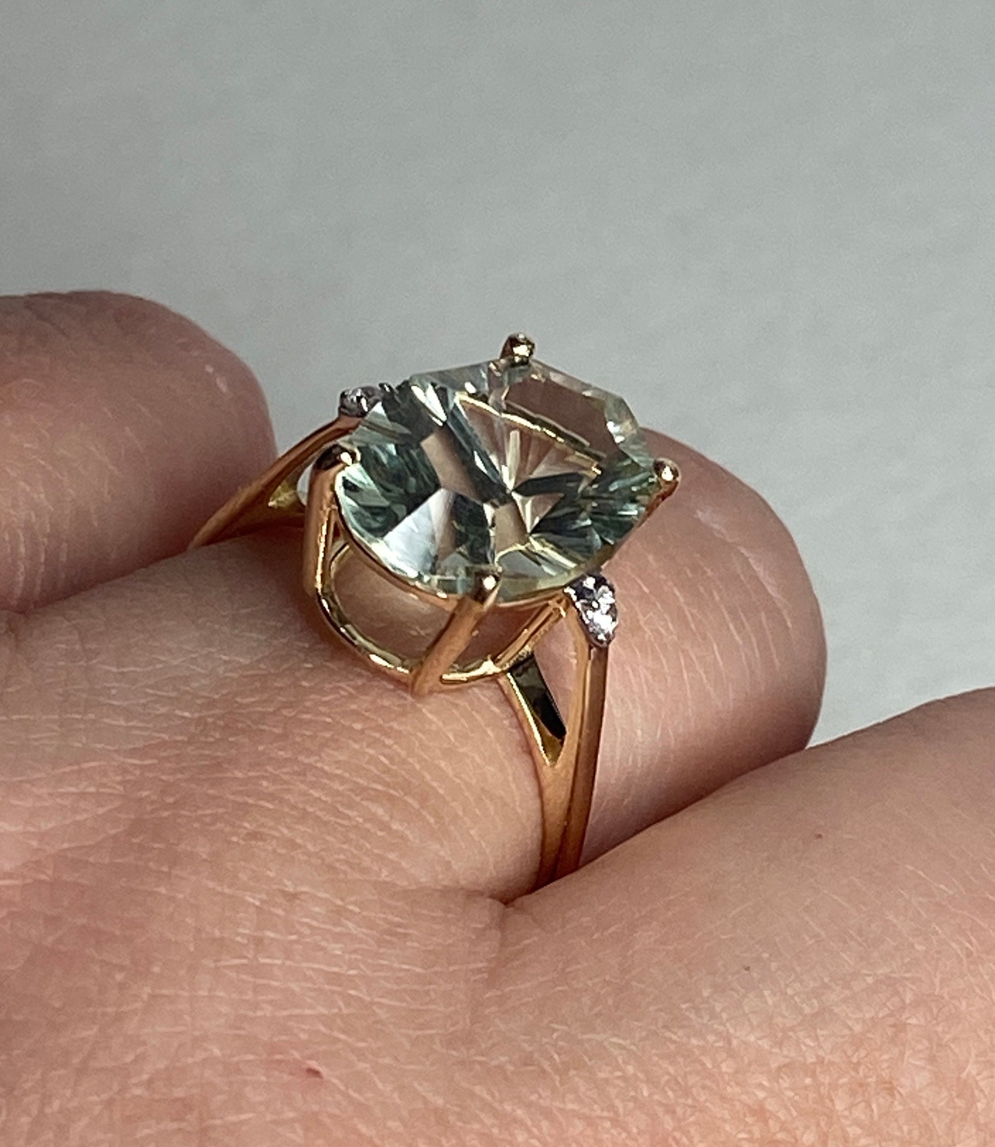 A 9k yellow gold ring with a large fancy cut prasiolite green quartz and two zircons.