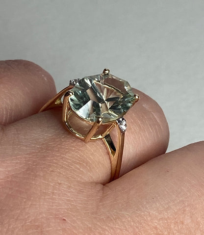 A 9k yellow gold ring with a large fancy cut prasiolite green quartz and two zircons.