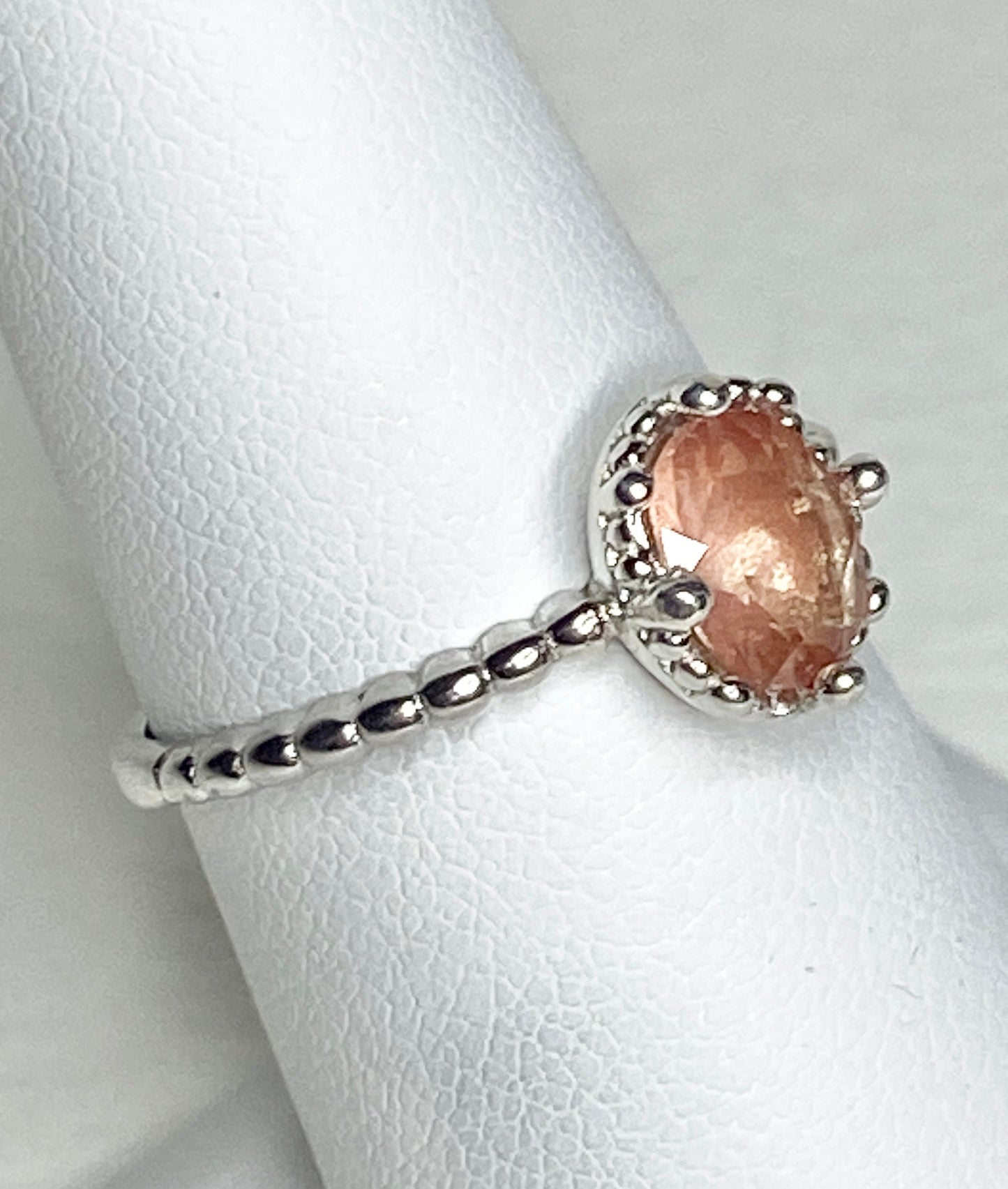 Sterling silver ring with a peach oval sunstone and beaded band.