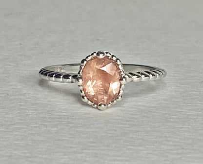 Sterling silver ring with a peach oval sunstone and beaded details.