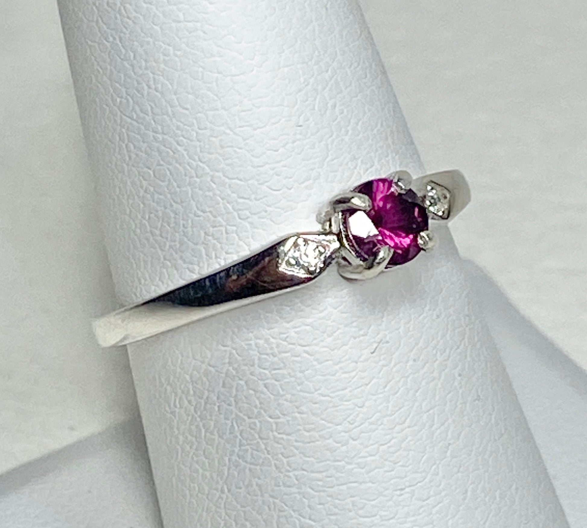 Sterling silver band ring with a purple rhodolite garnet and two small cz stones.