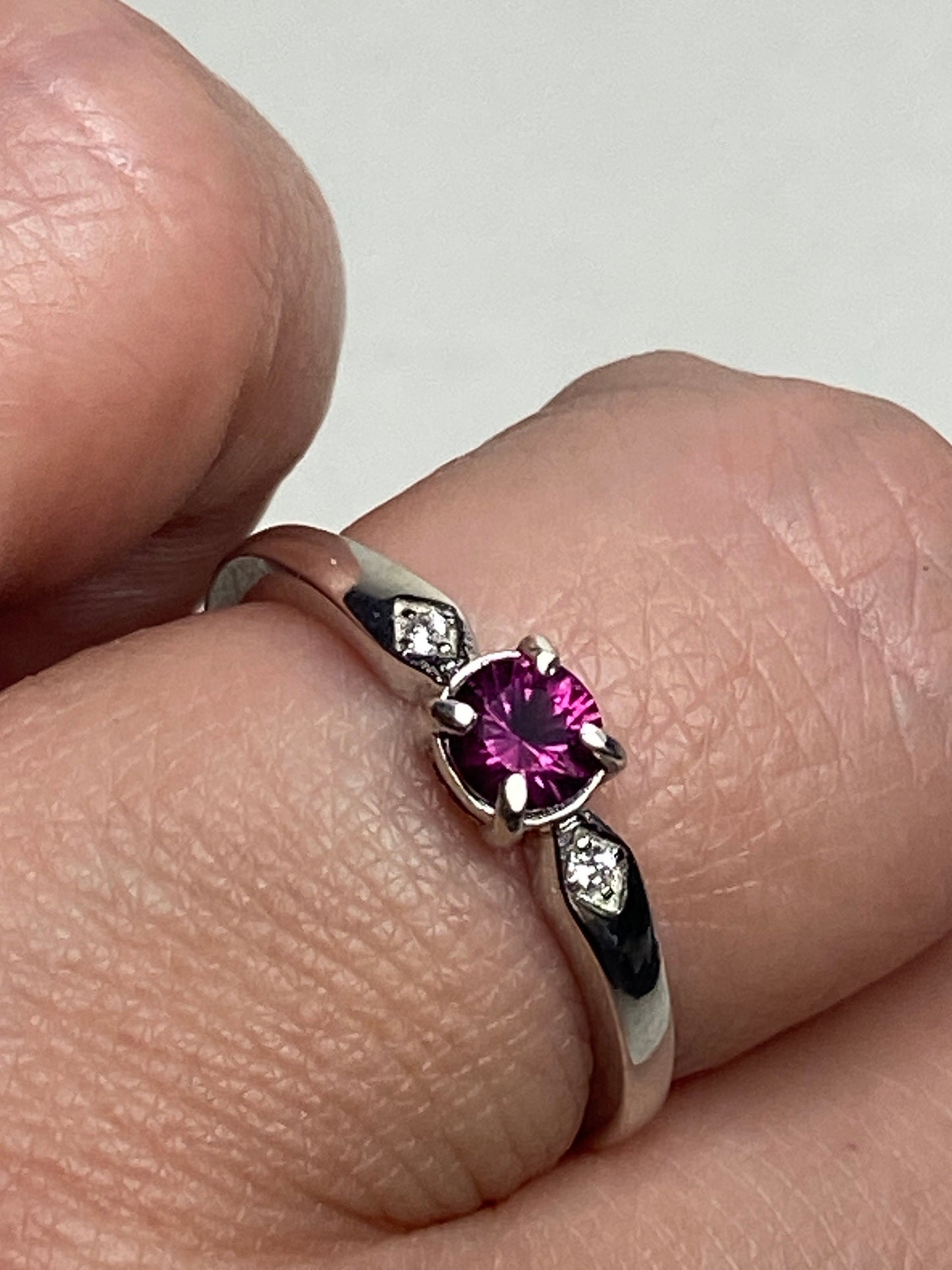 A sterling silver band ring with a purple rhodolite garnet and two small cz stones.