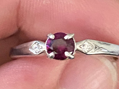 A sterling silver band ring with a purple rhodolite garnet and two small crystals.