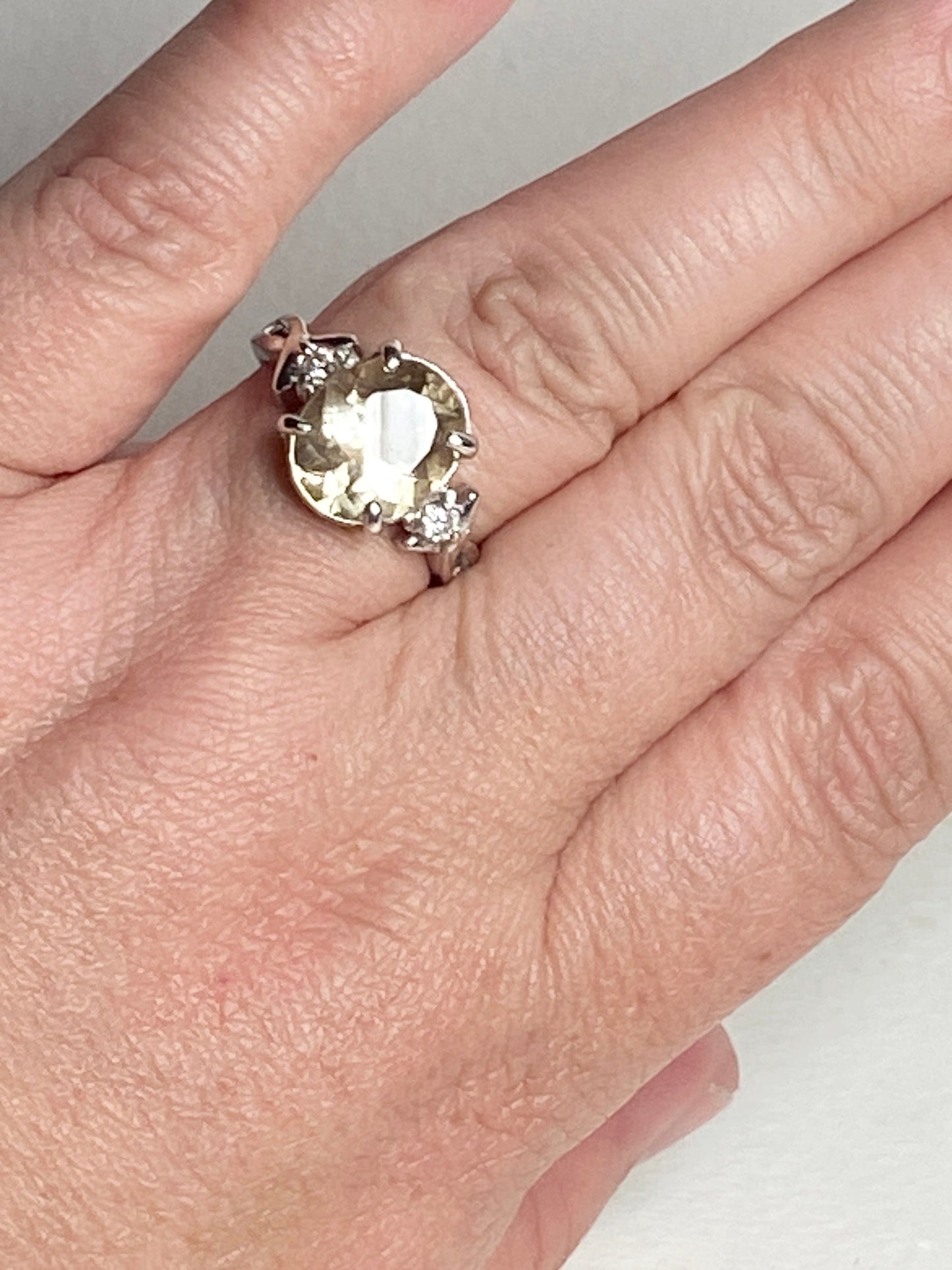 Sterling silver ring with a yellow oval sunstone and two diamonds.