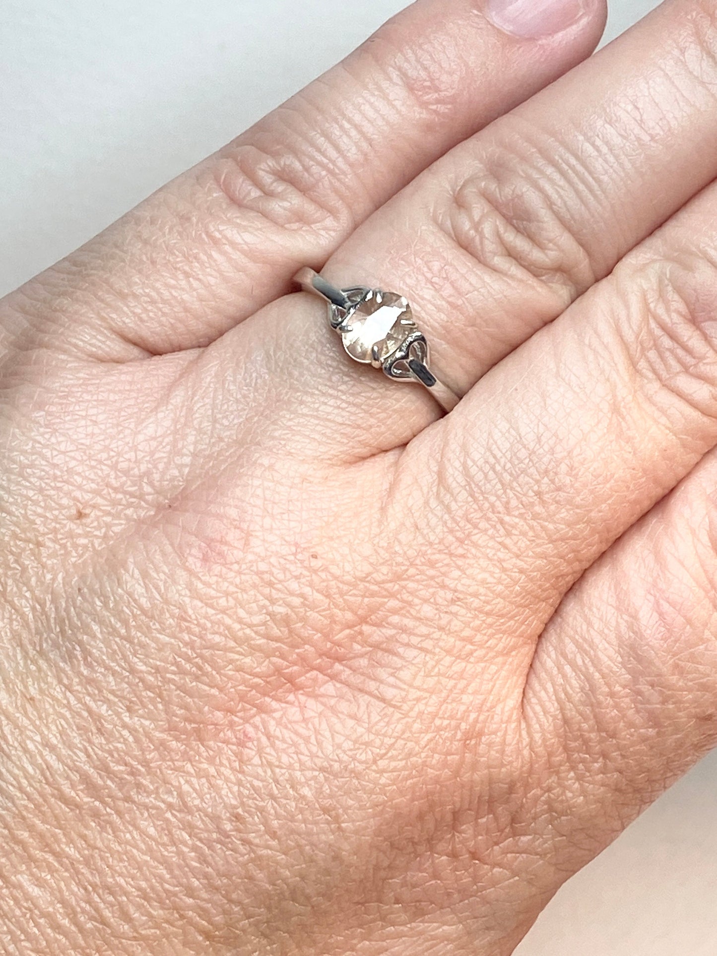 Sterling silver ring with a light peach Oregon sunstone and heart accents.