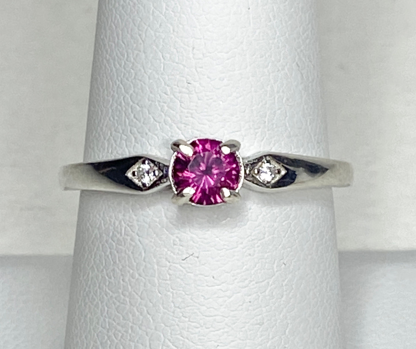 Sterling silver band ring with a pink rhodolite garnet and two small diamonds.