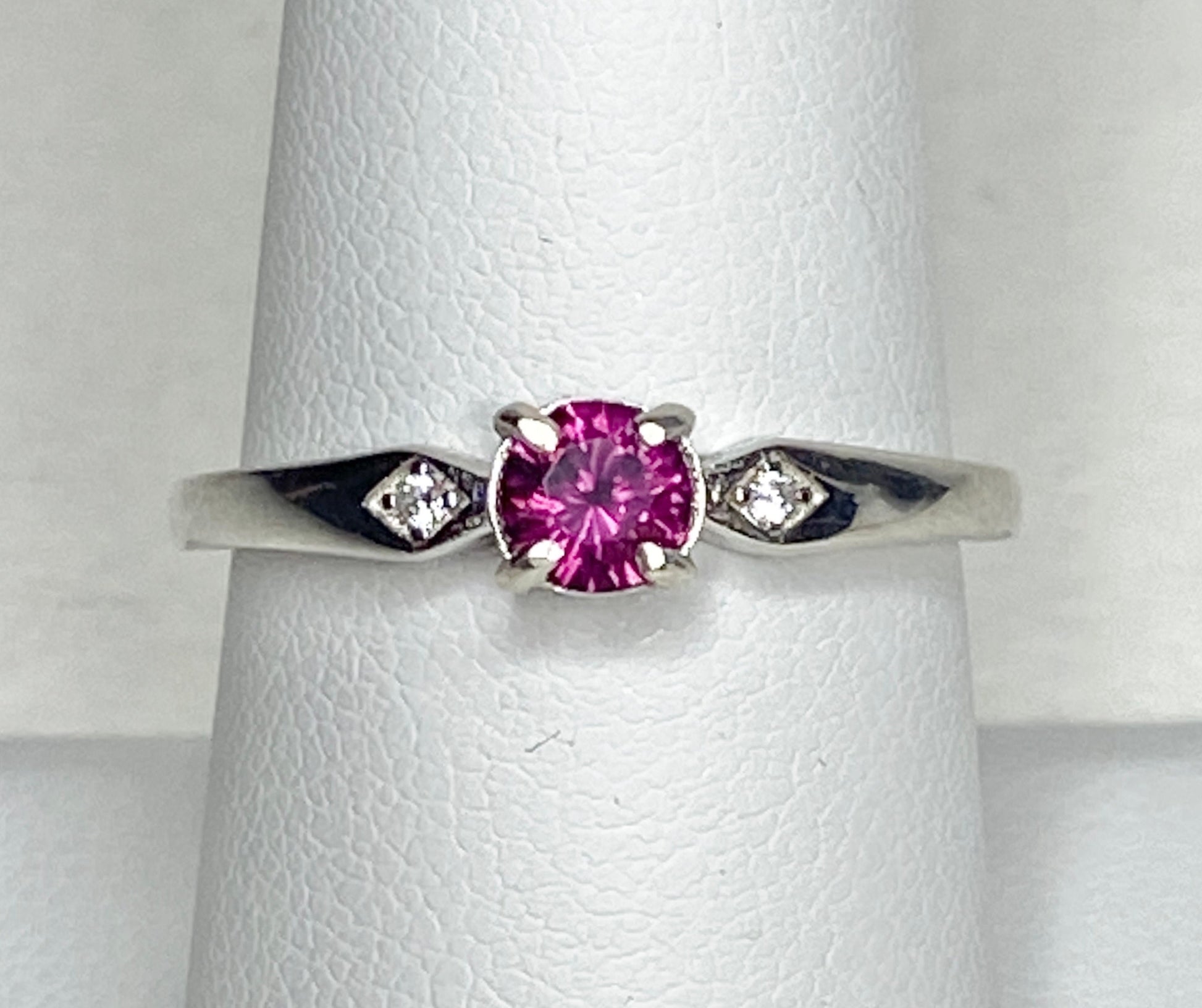 Sterling silver band ring with a pink rhodolite garnet and two small diamonds.