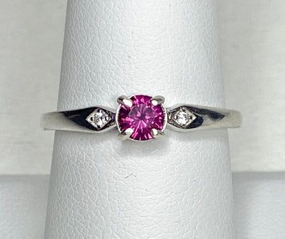 Sterling silver band ring with a pink rhodolite garnet and two small diamonds.