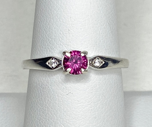 Sterling silver band ring with a pink rhodolite garnet and two small diamonds.