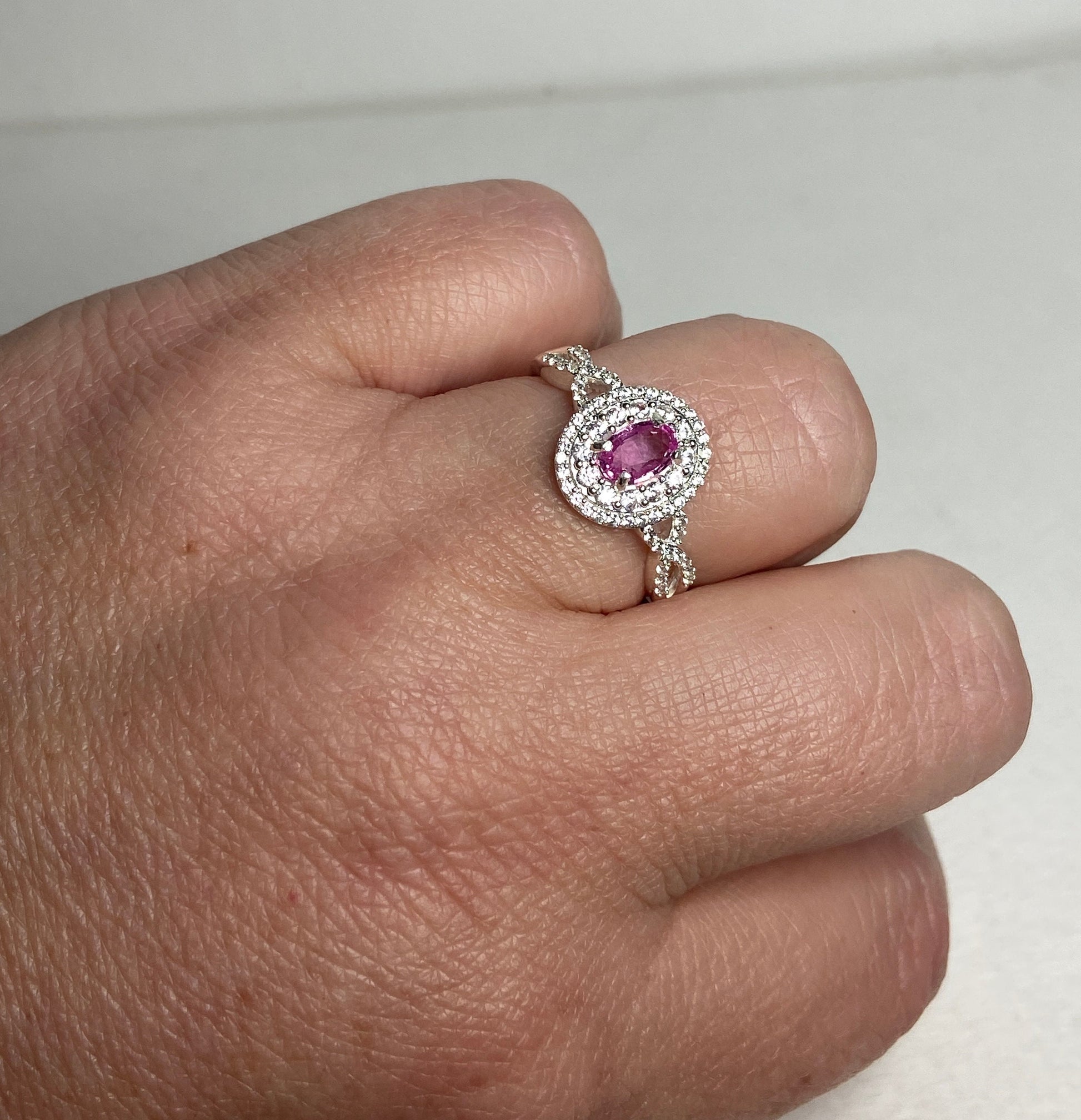 Sterling silver ring with oval pink sapphire and double halo of zircon.