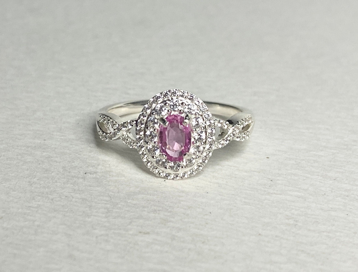 Oval pink sapphire ring with double zircon halo in sterling silver.