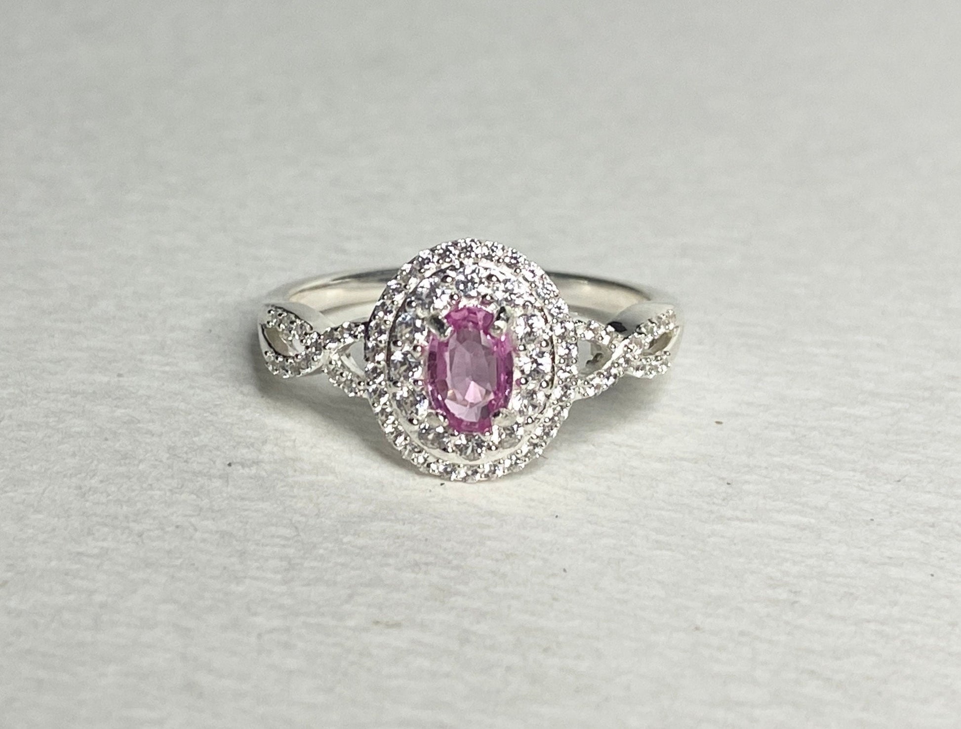 Oval pink sapphire ring with double zircon halo in sterling silver.
