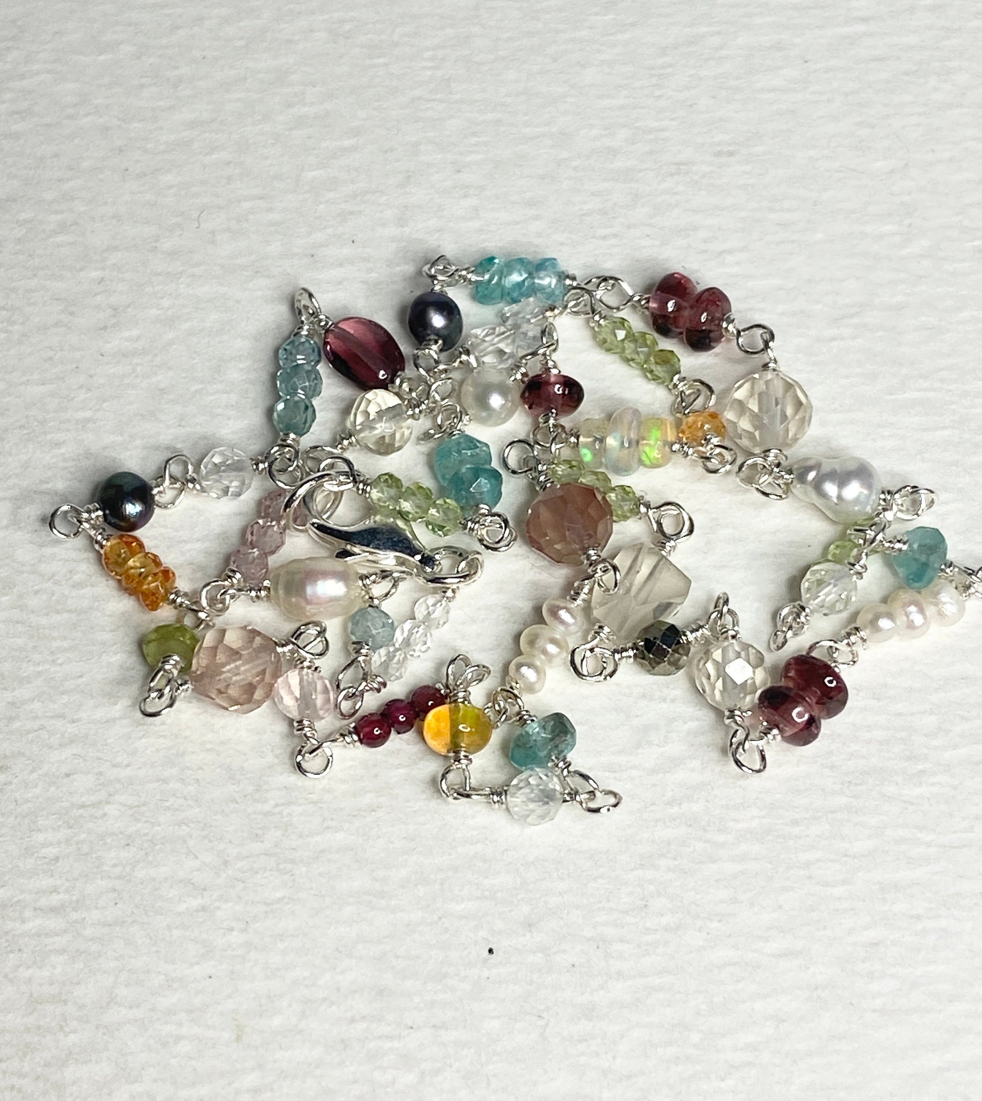 A multi-gemstone necklace with sterling silver findings and a variety of colorful beads.