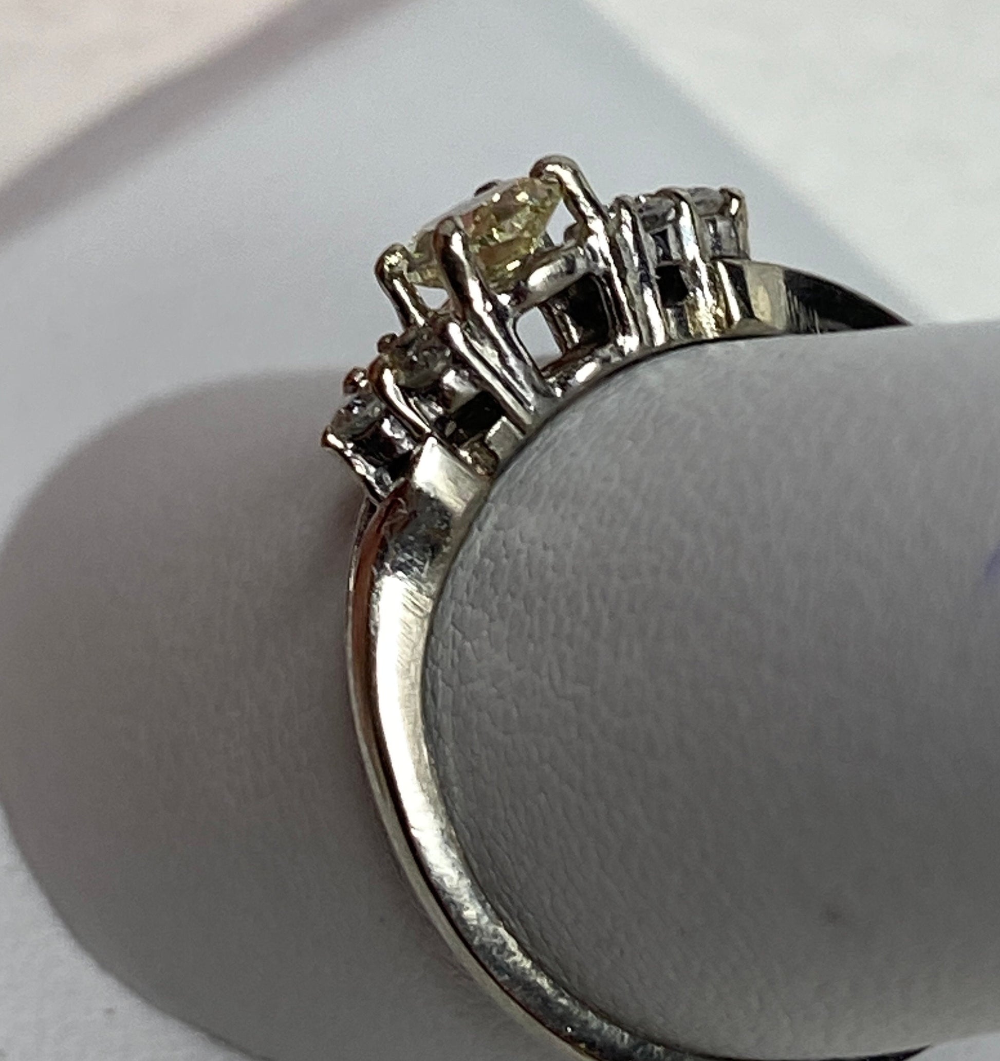 A 14k gold ring with a light yellow oval diamond and white side diamonds.