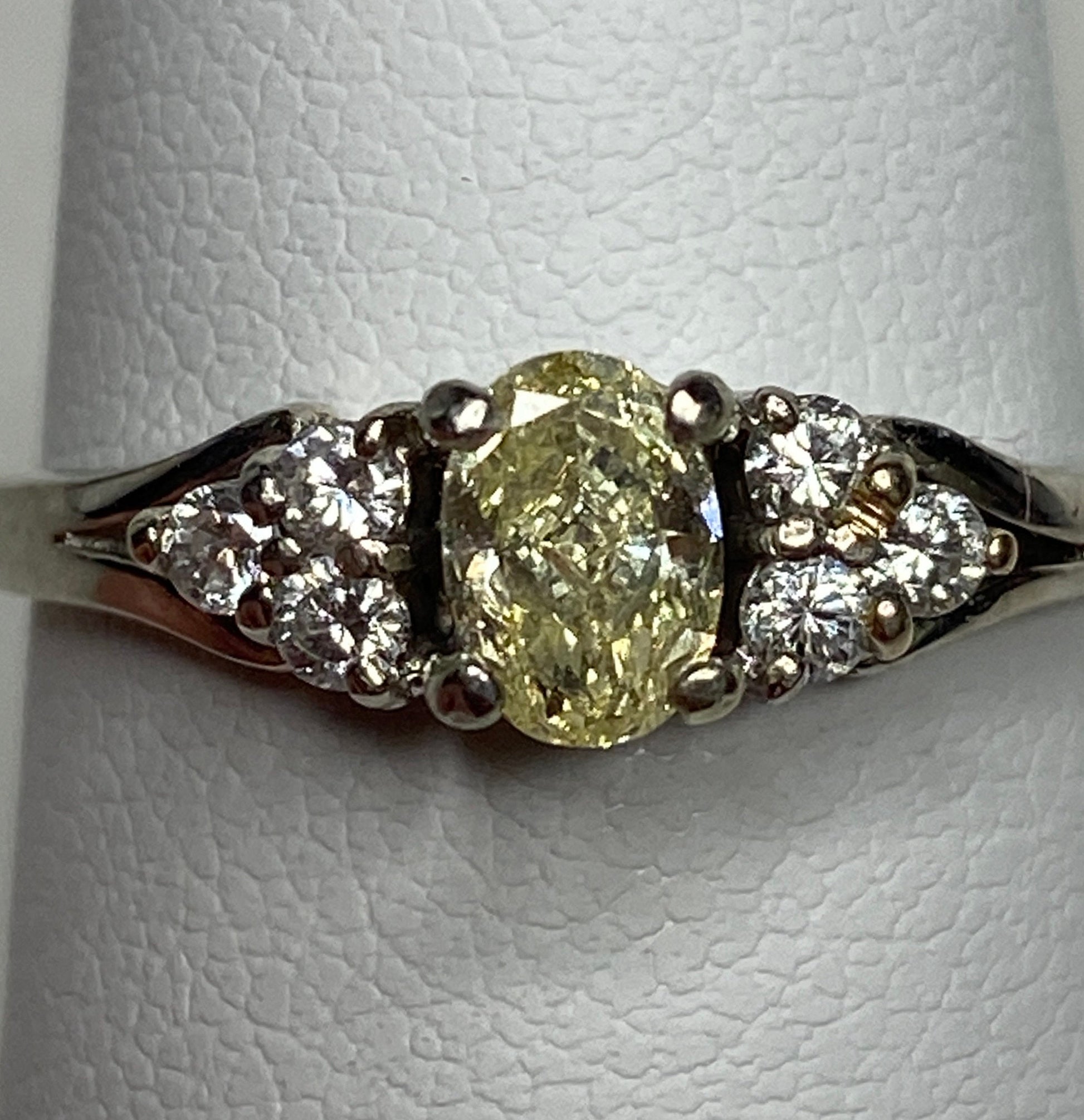 GIA certified oval fancy light yellow diamond ring with white diamonds in 14k gold.