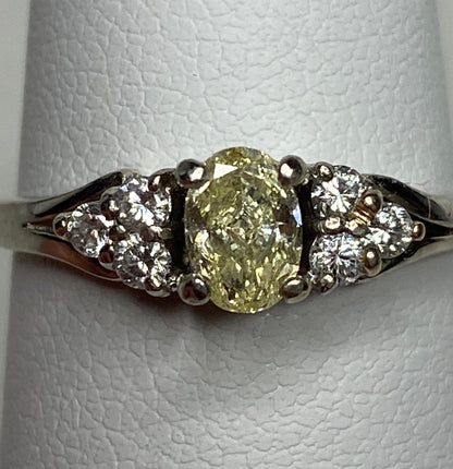 GIA certified oval fancy light yellow diamond ring with white diamonds in 14k gold.