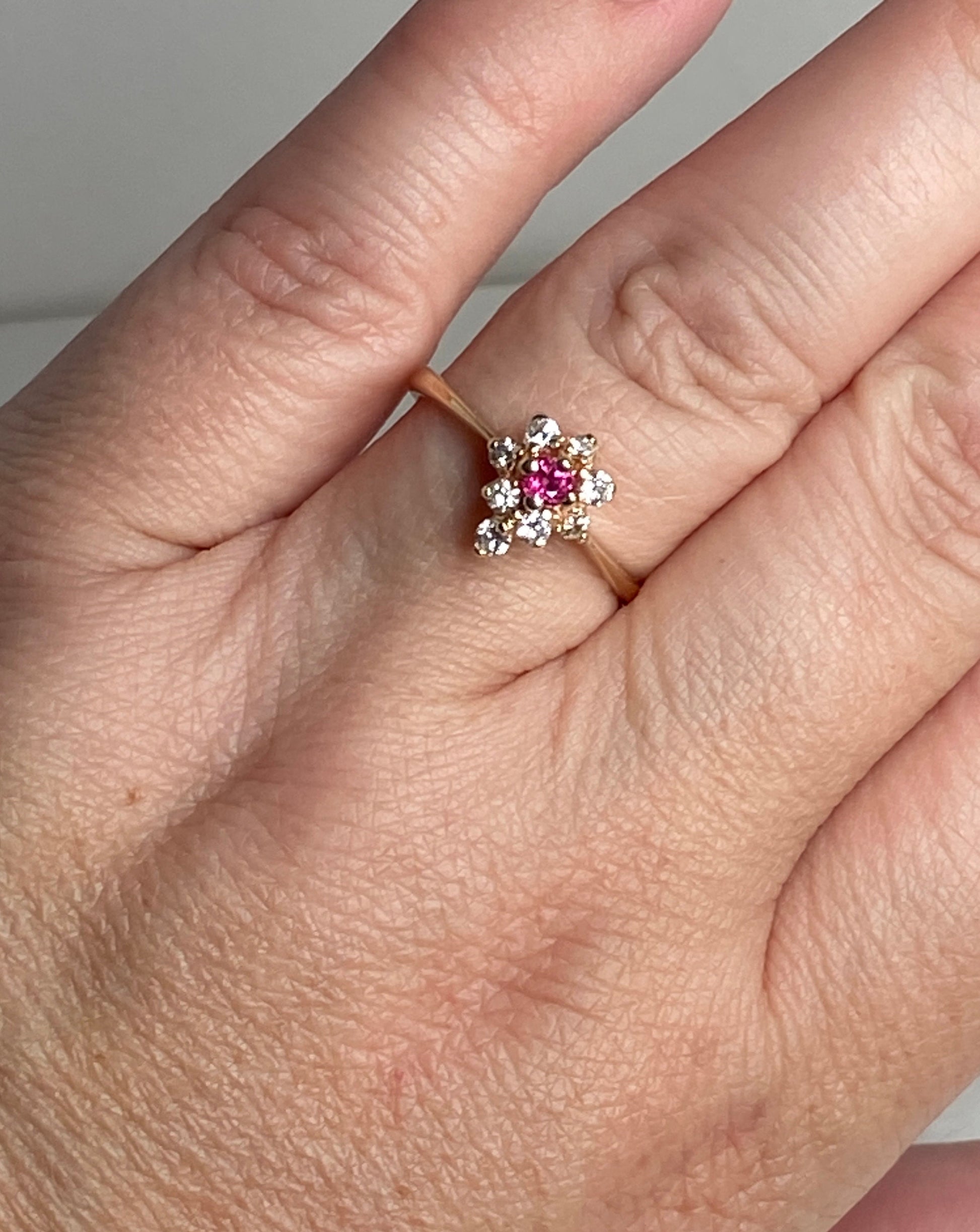 A 14k gold ring with a central rubellite tourmaline surrounded by diamonds.