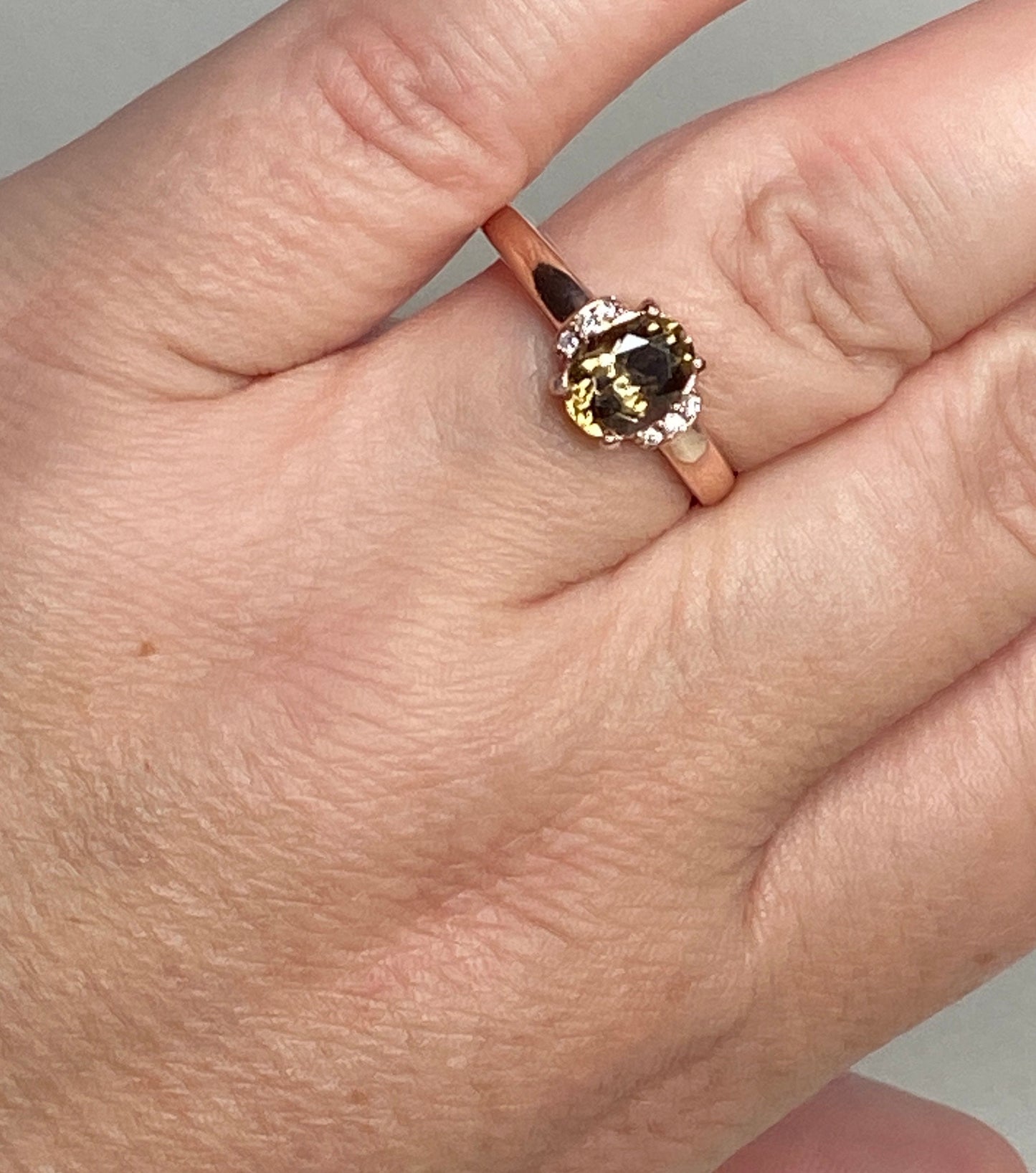 10k rose gold ring with oval greenish-gold zircon and flanking diamonds.