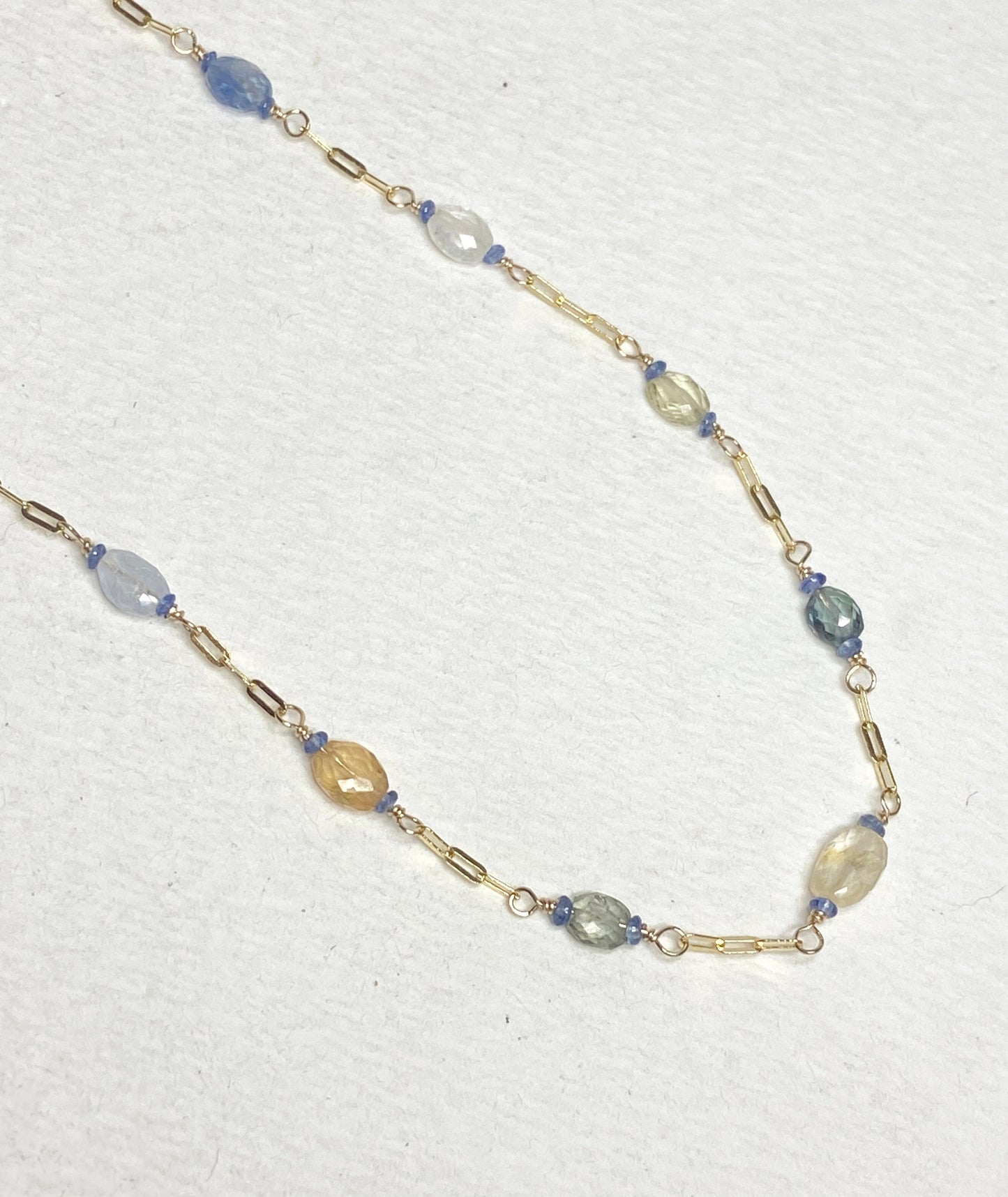 A 14k gold station chain necklace with multi-colored sapphires.