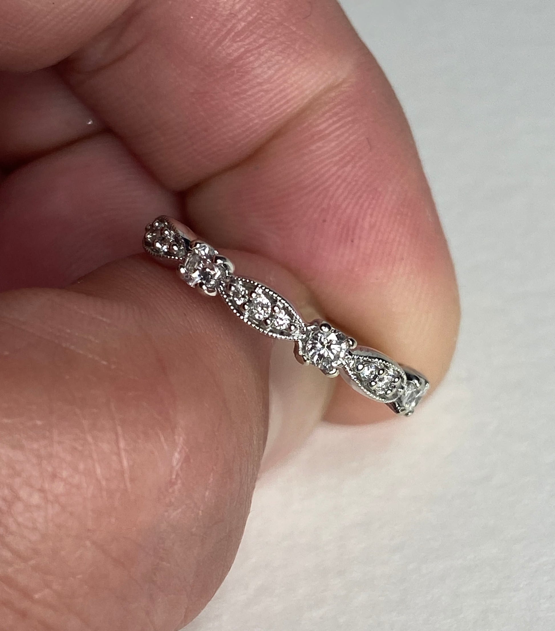 A delicate 10k white gold band ring with small diamonds and milgrain detailing.