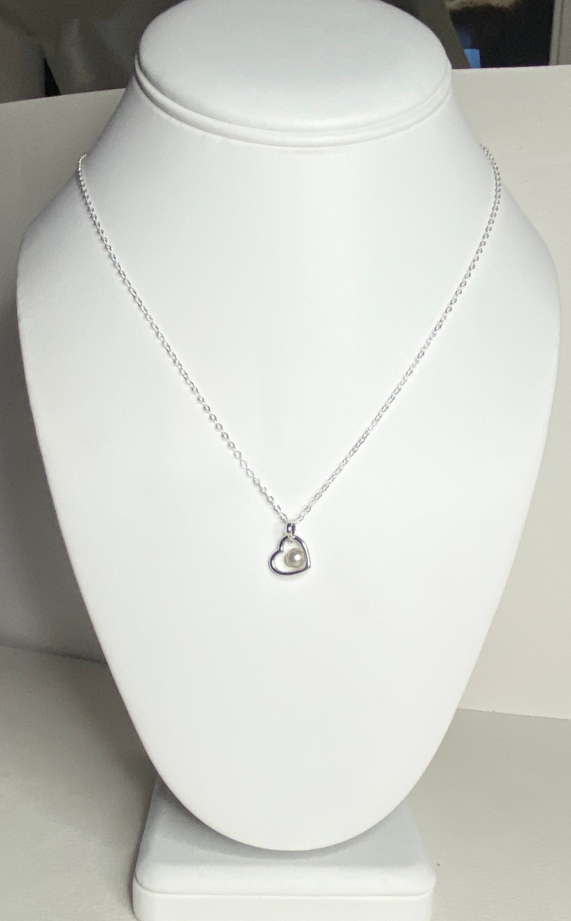 Sterling silver necklace with a heart pendant holding a cultured akoya pearl.
